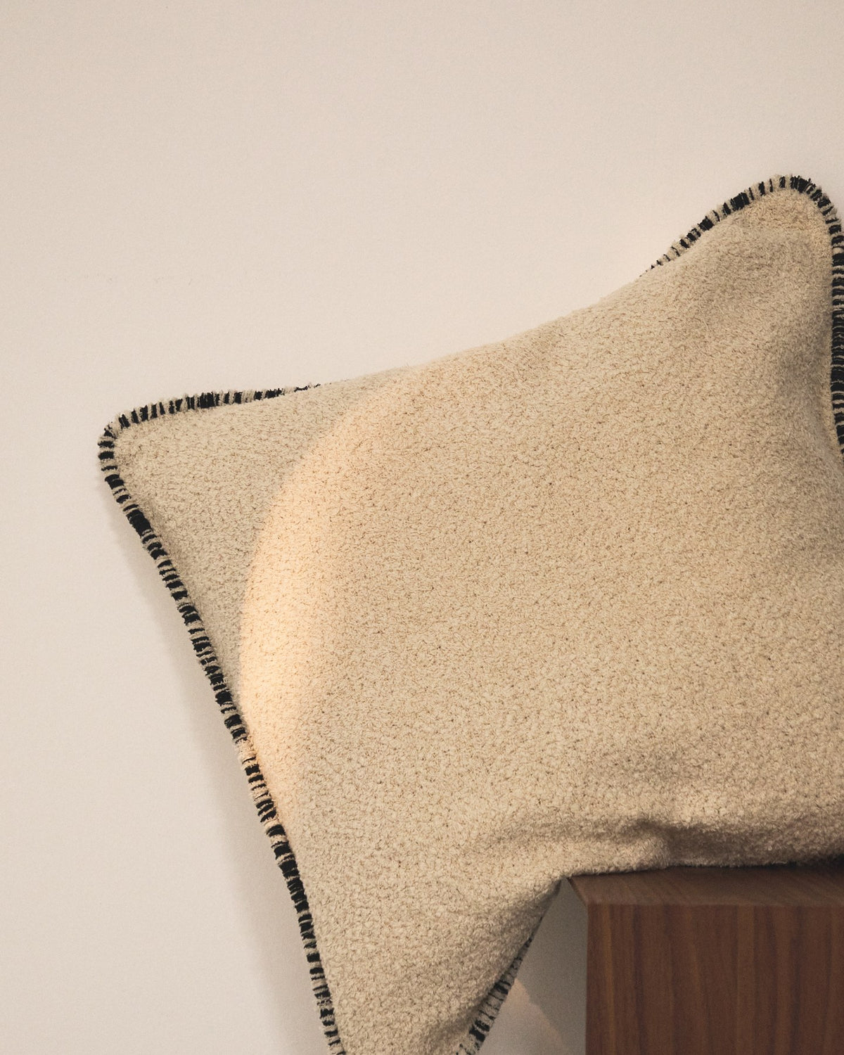 Quadratischer Kissenbezug aus Baumwoll-Bouclé in Beige mit schwarzer Kontrastpaspel und Reissverschluss, Grösse 50 x 50 cm.