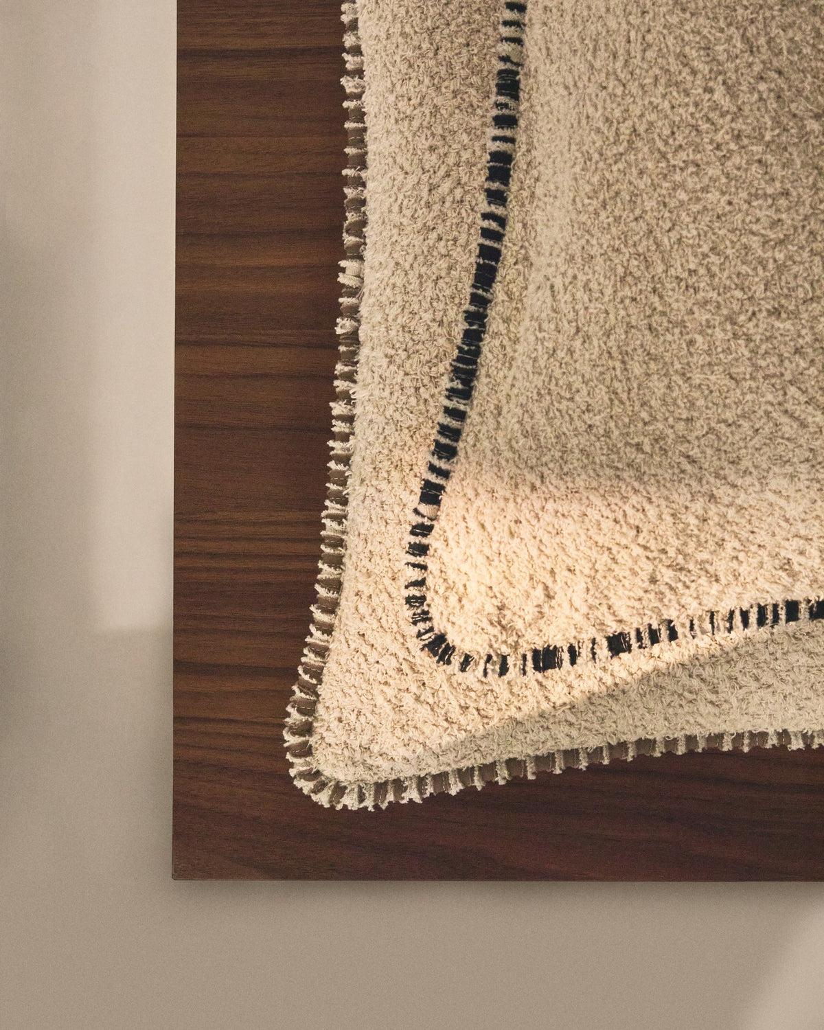 Quadratischer Kissenbezug aus Baumwoll-Bouclé in Beige mit schwarzer Kontrastpaspel und Reissverschluss, Grösse 50 x 50 cm.