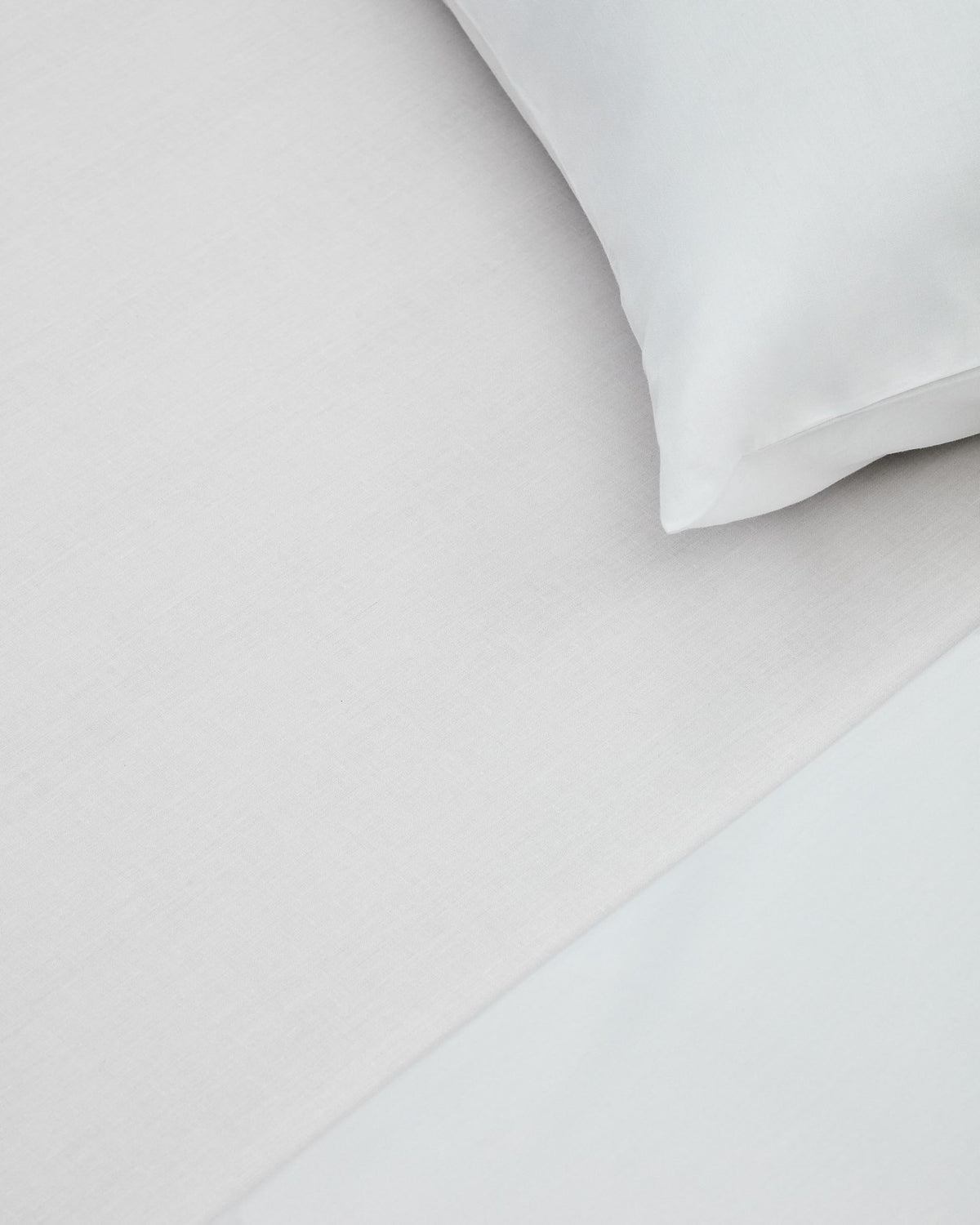 Weisses Spannbettlaken aus 100% Baumwollperkal mit 180 Fäden, gespannt auf einer Matratze für ein Bett von 160 cm.
