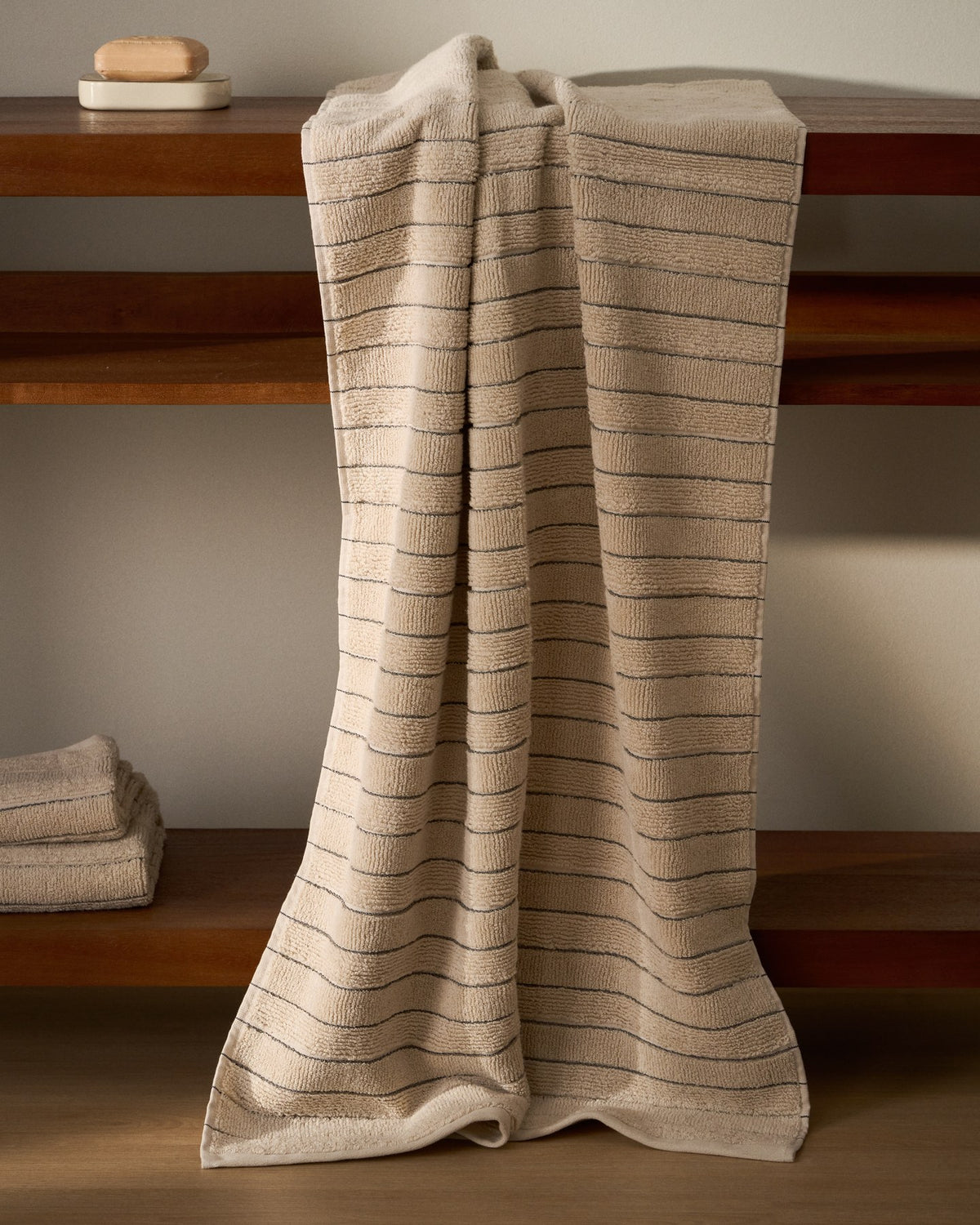 Beiges Badetuch aus Jacquard-Baumwolle mit Streifenmuster, Format 70 x 140 cm, gefaltet auf hellem Untergrund fotografiert.