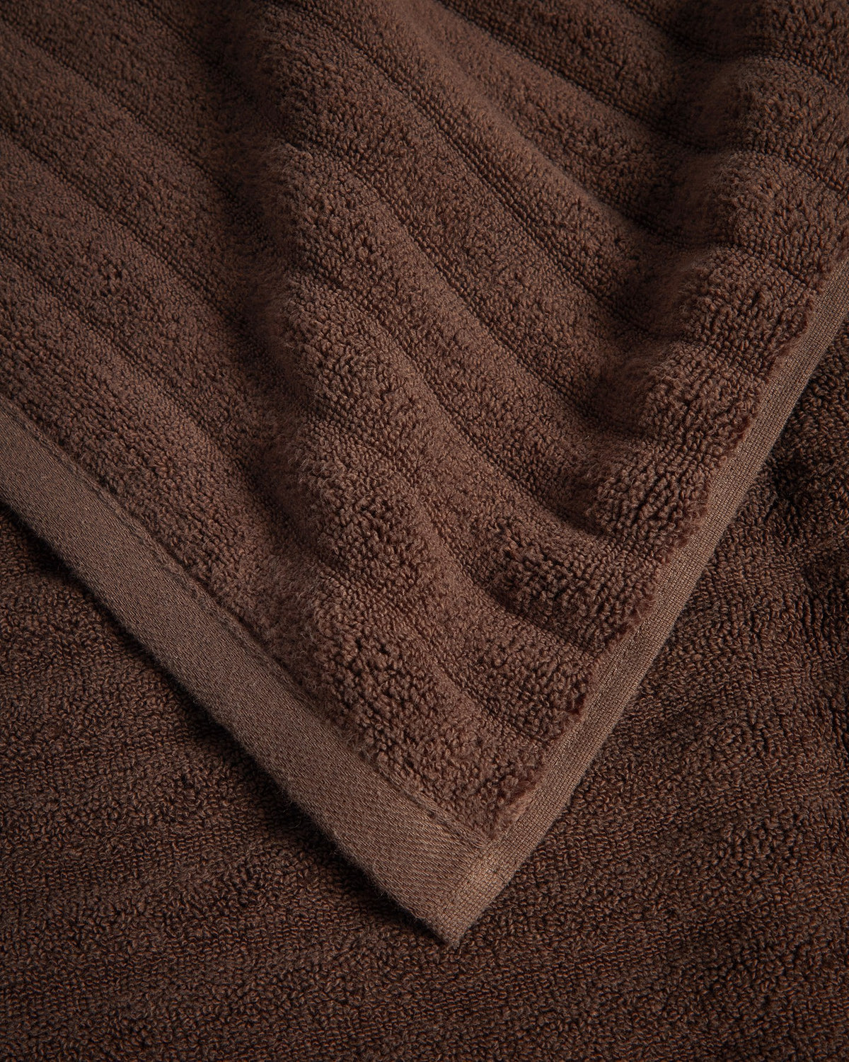 Granatrotes Toilettenhandtuch aus 100 % Baumwolle mit welliger Struktur, Grösse 30 x 50 cm, liegt gefaltet auf hellem Untergrund.