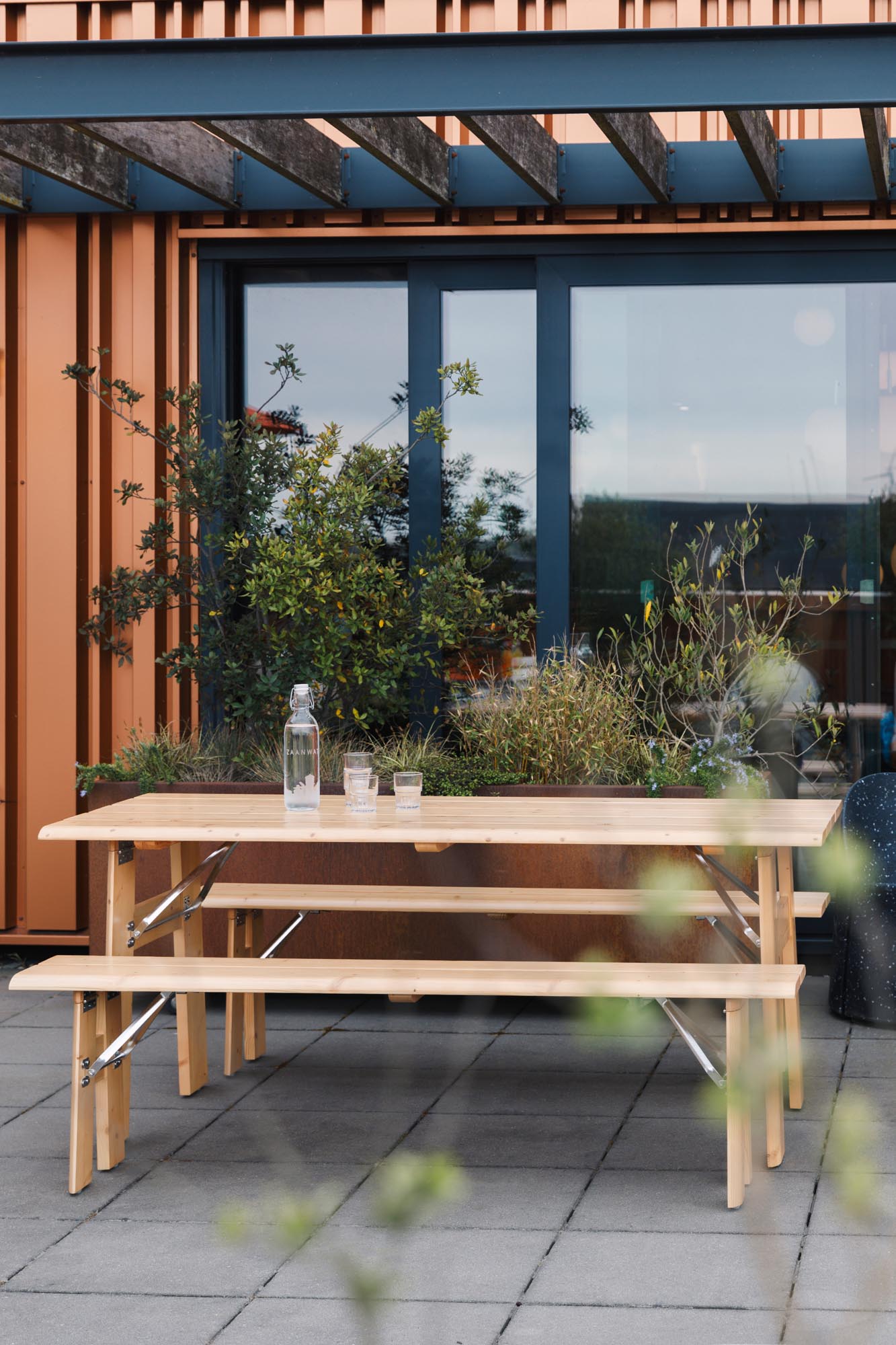 Erleben Sie das elegante Gartentischset Avenue von Zuiver – klappbar, mit integriertem Flaschenöffner und ideal für entspannte Momente im Freien.