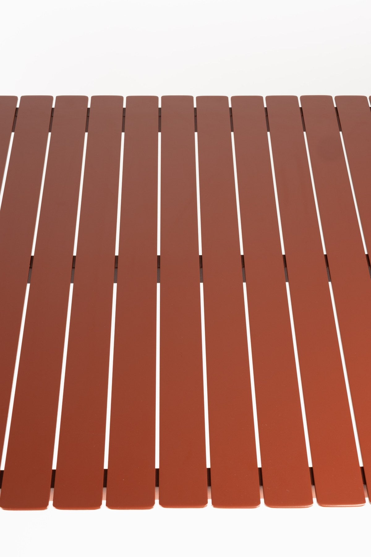 Roter Gartentisch Vondel von Zuiver aus pulverbeschichtetem Aluminium mit rechteckiger Tischplatte und schlanken Beinen im Freien.