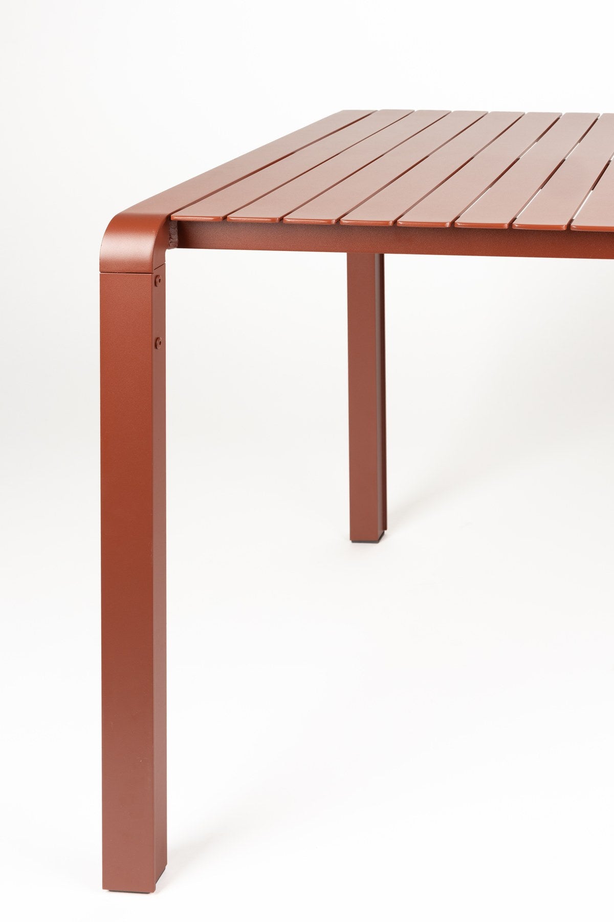 Roter Gartentisch Vondel von Zuiver aus pulverbeschichtetem Aluminium mit rechteckiger Tischplatte und schlanken Beinen im Freien.