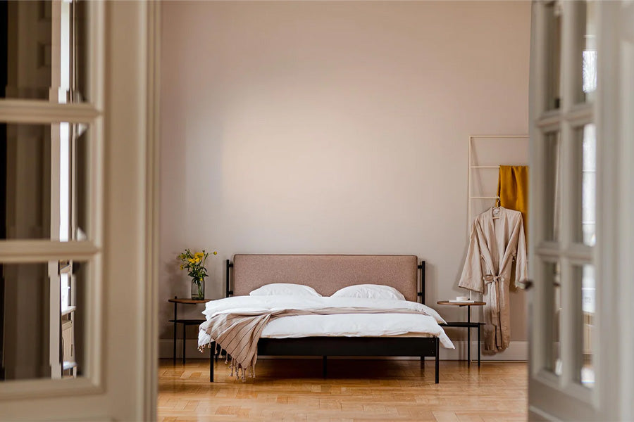 Das Noo.ma Eton Basic Bett zeigt ein modernes, minimalistisches Design mit gepolstertem Kopfteil und pulverbeschichtetem Stahlrahmen.