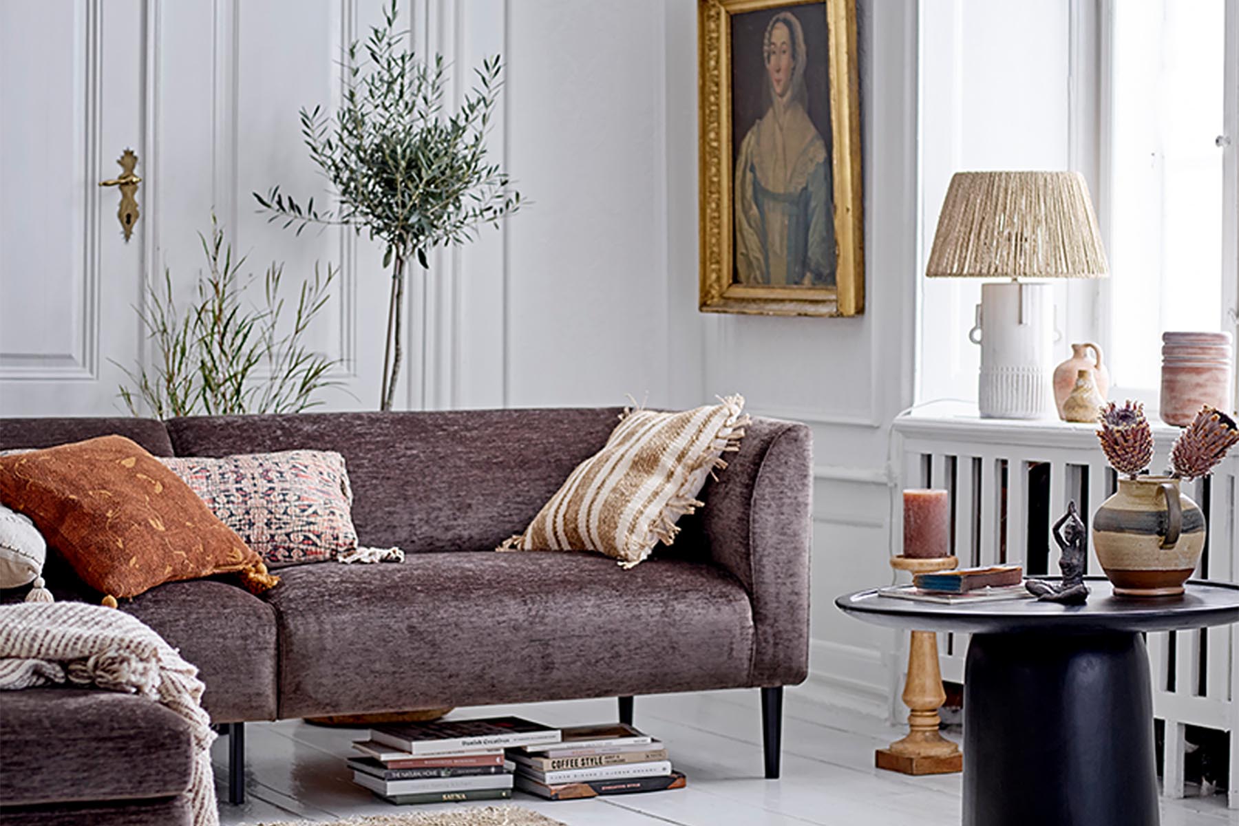 Ein gemütliches Wohnzimmer mit einem bequemen Sofa, dekoriert mit weichen Kissen und Decken, stimmungsvoller Beleuchtung und einer warmen Atmosphäre für entspannte Kuschelmomente.