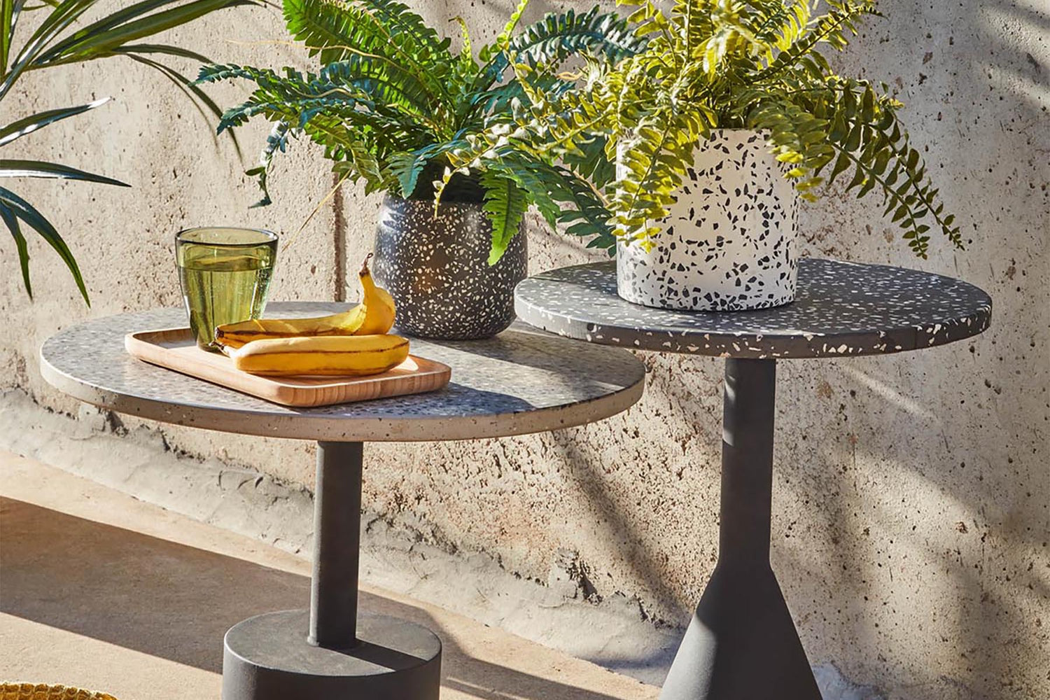 Ein stilvoll gestalteter Outdoor-Bereich mit einem modernen Lounge-Set in sanften Naturtönen, umgeben von grünen Pflanzen und dekorativen Elementen, inspiriert von den Outdoor-Trends 2025.