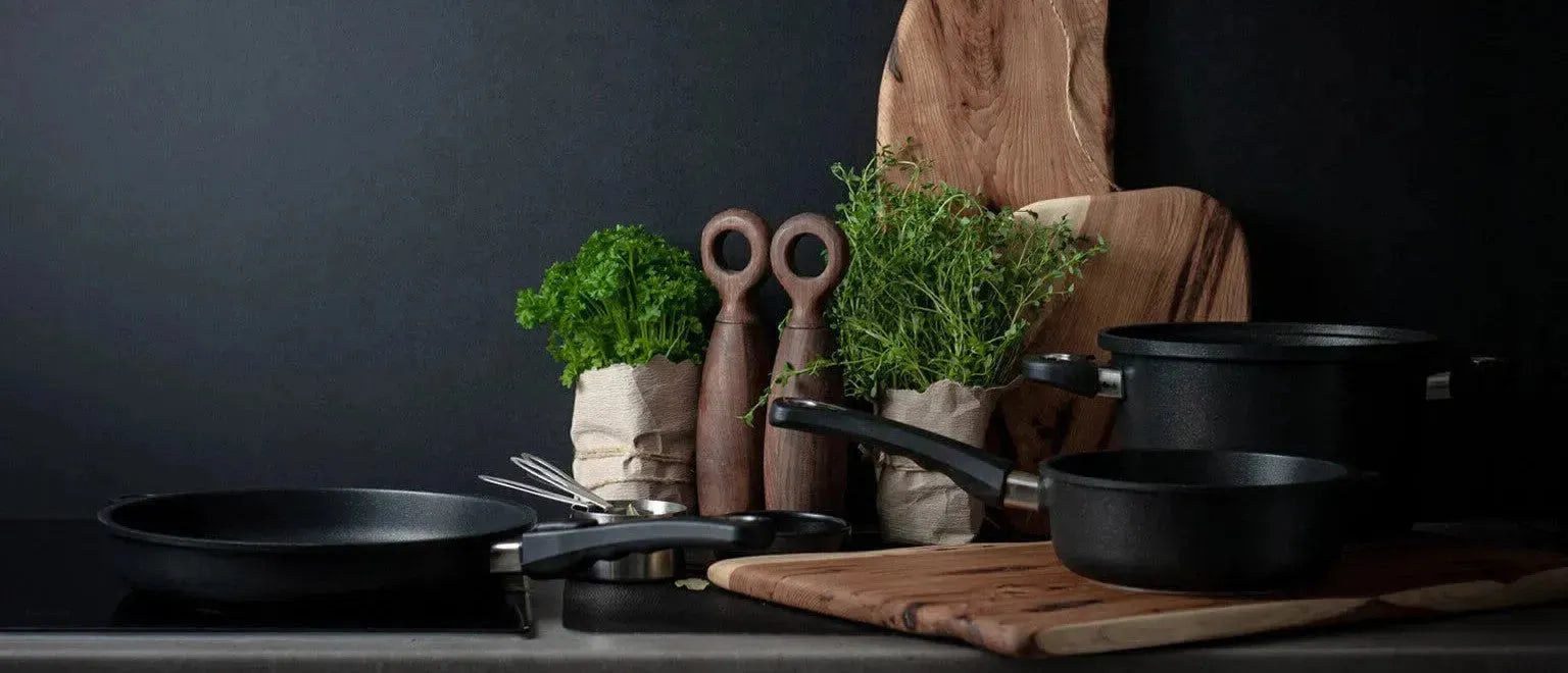 Premium Kochgeschirr der AMT Gastroguss Kollektion, präsentiert auf einer eleganten Küchenoberfläche mit Pfannen und Töpfen aus hochwertigem Aluminiumguss, ideal für vielseitige Kochanwendungen.