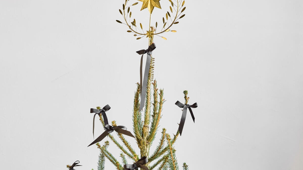 Goldener Stern als Christbaumschmuck am geschmueckten Weihnachtsbaum