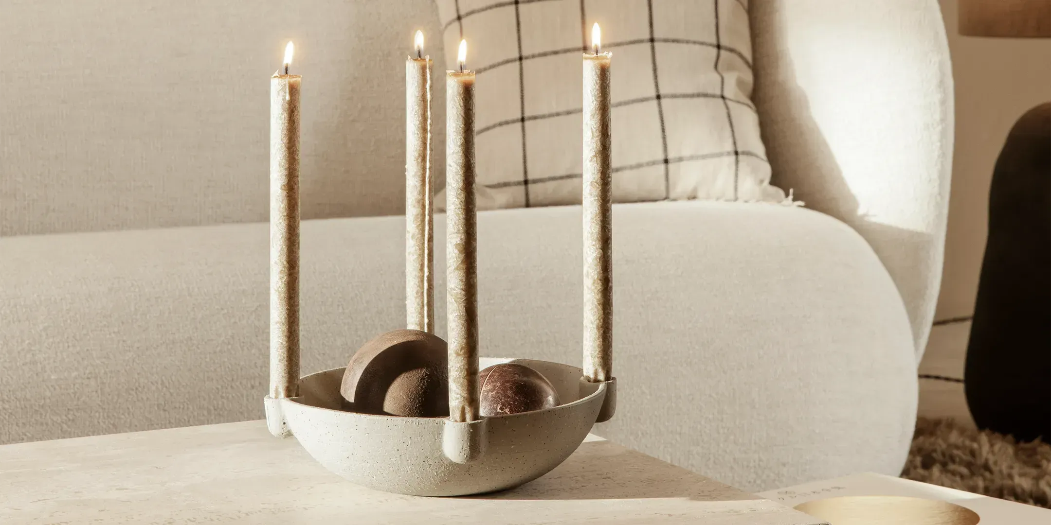 Kerzenständer und Kerzen in verschiedenen Designs und Materialien, dekorativ arrangiert auf einem Tisch, mit warmem und einladendem Ambiente.