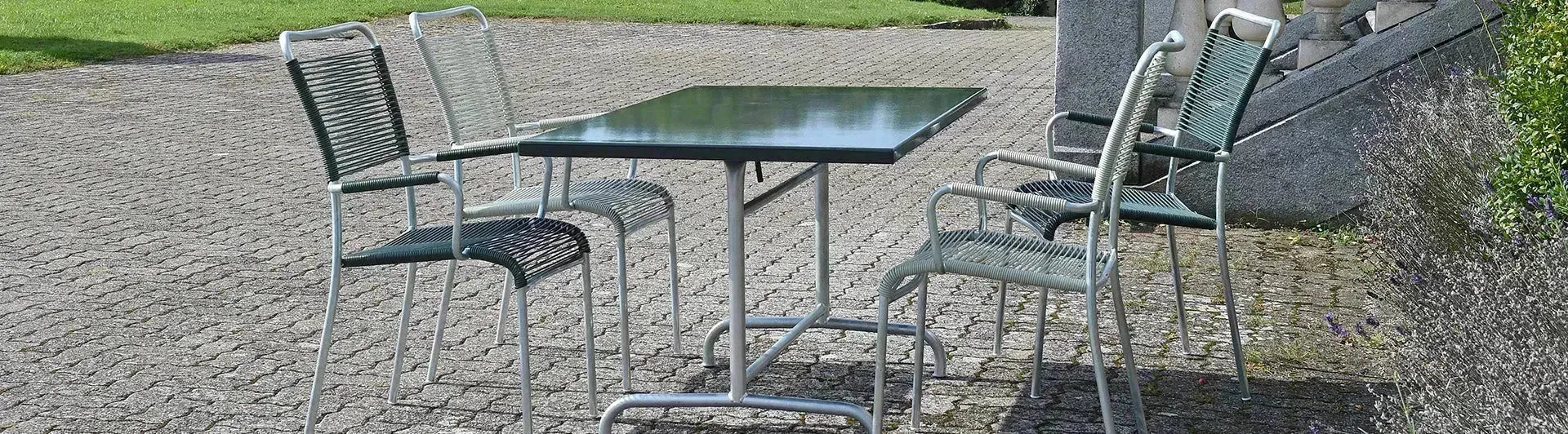 Farbenfrohe Spaghetti-Gartenstühle der Mendrisio-Serie von Schaffner, im Retro-Design der 60er-Jahre mit elastischen Kunststoffschnüren, Swiss Made, auf einer Terrasse arrangiert.