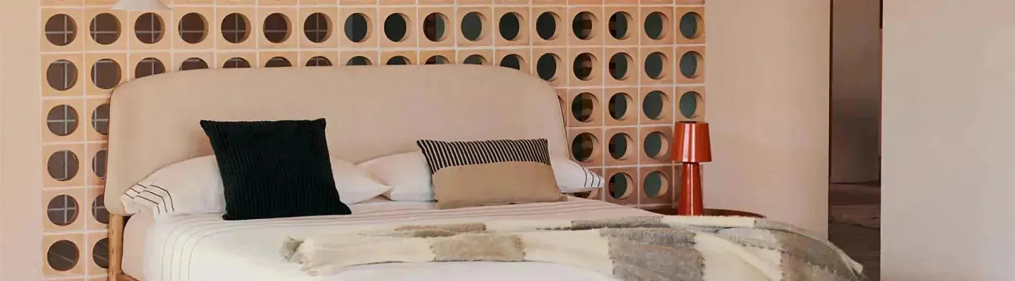 Schlafzimmer mit Möbeln der Octavia Kollektion von Kave Home: Bettgestell aus Eschenfurnier, runde Nachttische und schwebendes Wandregal in natürlichem Holzdesign, kombiniert mit warmen Textilien und harmonischen Formen.