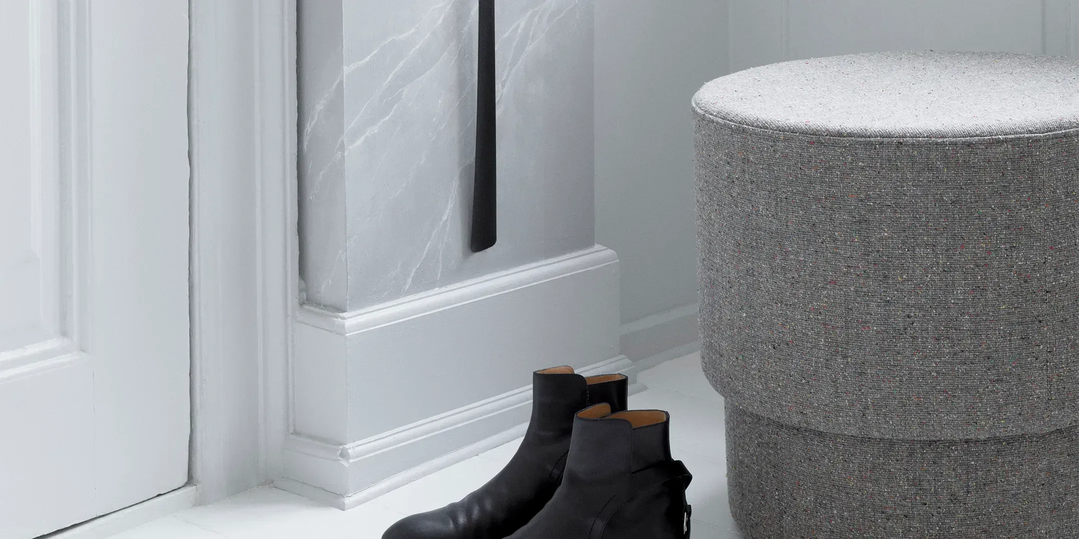 Ein stilvoll arrangierter Pouf in modernem Design, umgeben von gemütlichen Wohnaccessoires, ideal als Fusshocker, Sitzgelegenheit oder dekoratives Element.