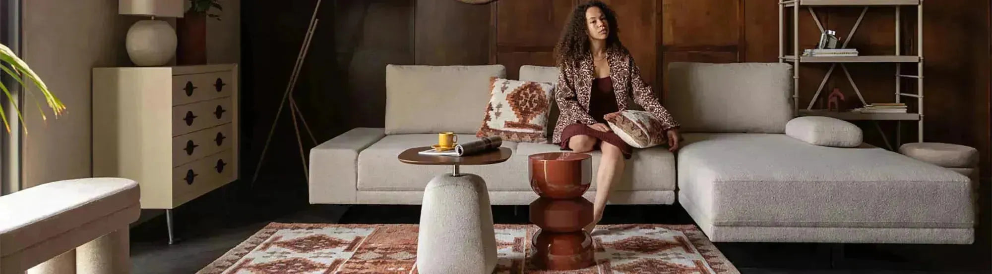 Elegantes Sofa der Shelly-Serie von Dutchbone mit geschwungenen Linien, weichem Stoffbezug und Holzbeinen, das modernes Design und zeitlose Ästhetik vereint.