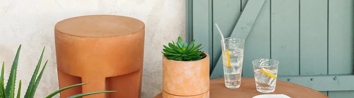 Outdoor Hocker auf einer Terrasse, umgeben von Pflanzen, ideal als stilvolle und praktische Sitzgelegenheit für Garten, Balkon oder Terrasse.