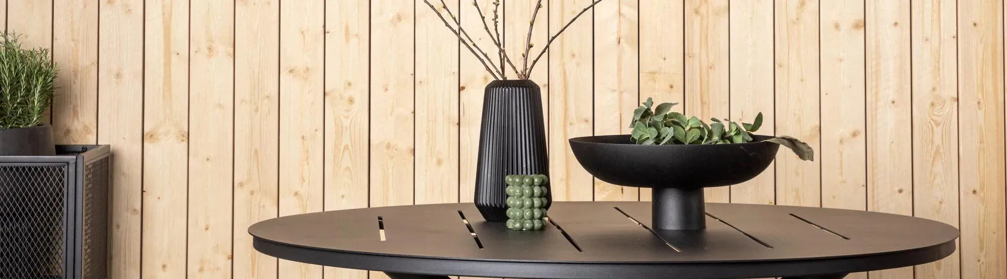 Stilvolle und platzsparende Outdoor-Möbel auf einem kleinen Balkon, darunter ein klappbarer Tisch, stapelbare Stühle und dekorative Pflanzgefäße, ideal für begrenzte Außenbereiche.