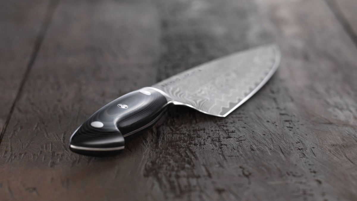 Zwilling Kramer Euro Stainless Kochmesser mit Damastklinge auf einem Schneidebrett aus Holz