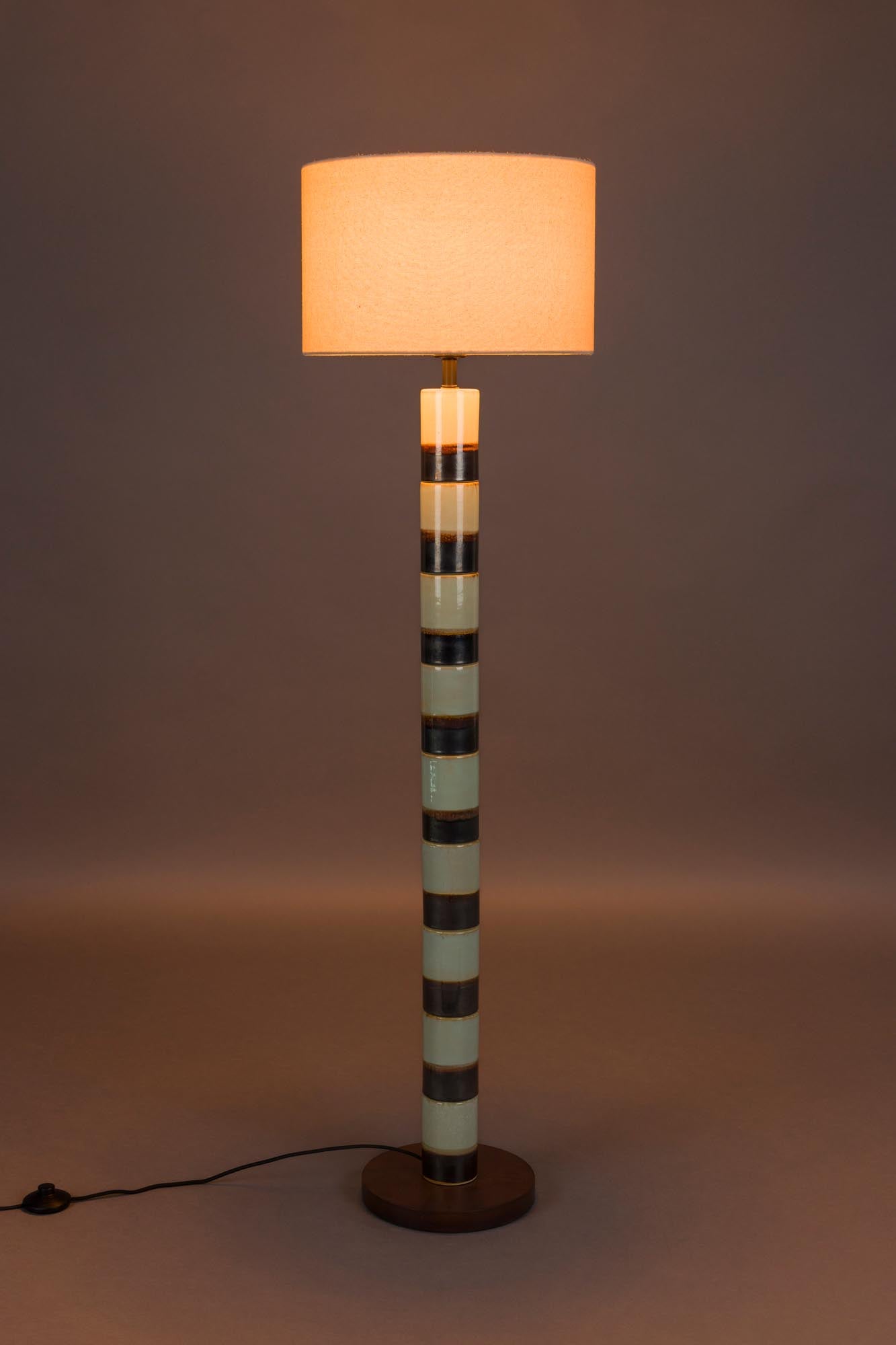 Die Stehlampe Vertigo von Dutchbone: Ein kunstvolles Designstück aus Eisen und Walnussholz, das warmes Licht und Stil vereint.