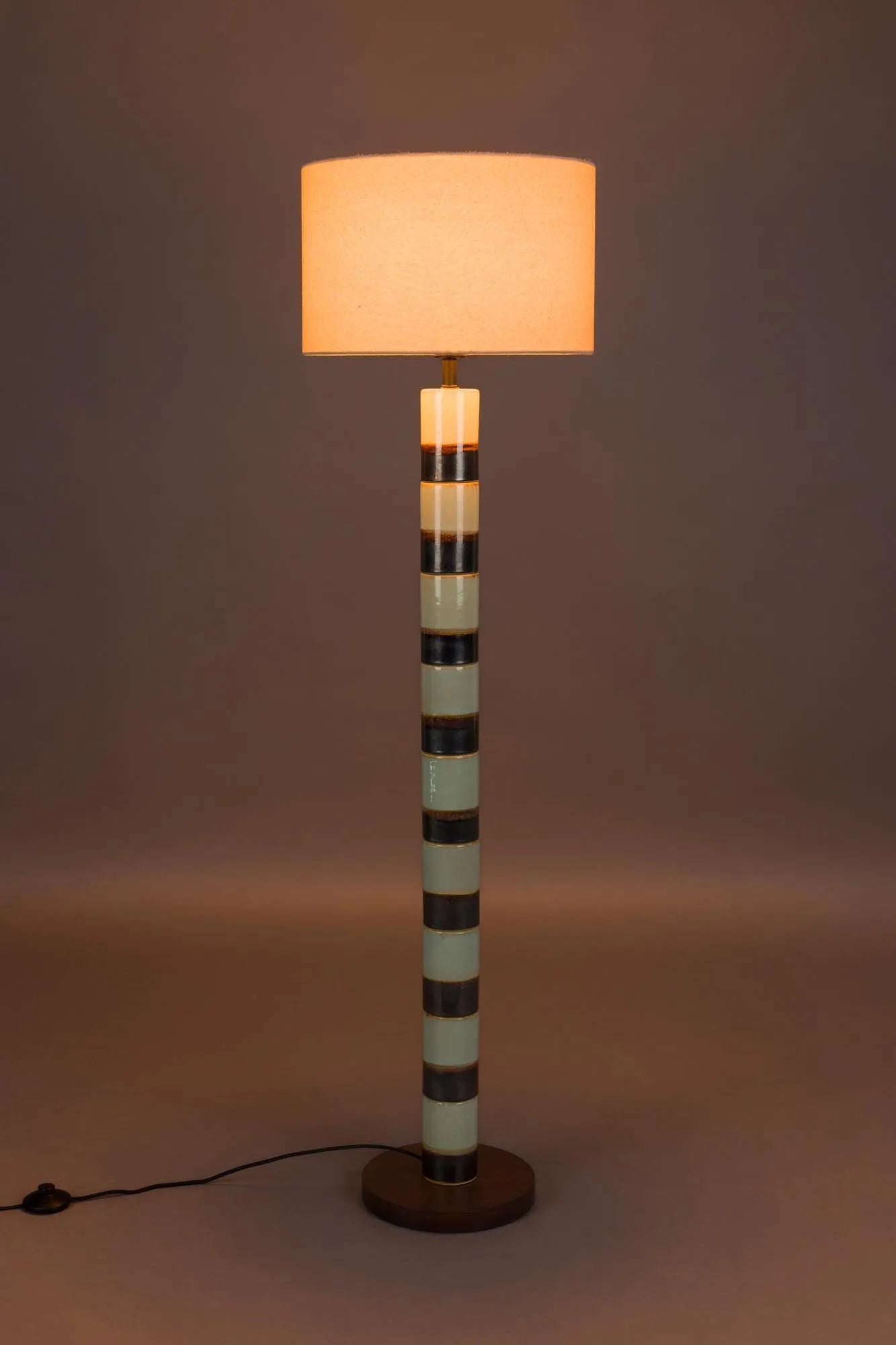 Die Stehlampe Vertigo von Dutchbone: Ein kunstvolles Designstück aus Eisen und Walnussholz, das warmes Licht und Stil vereint.