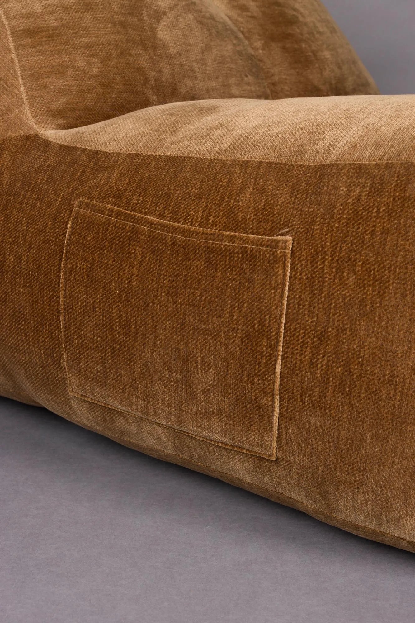 Der Loungesessel Tombag von Dutchbone: Stilvoller Komfort mit samtiger Oberfläche, praktischer Seitentasche und nostalgischem Flair.