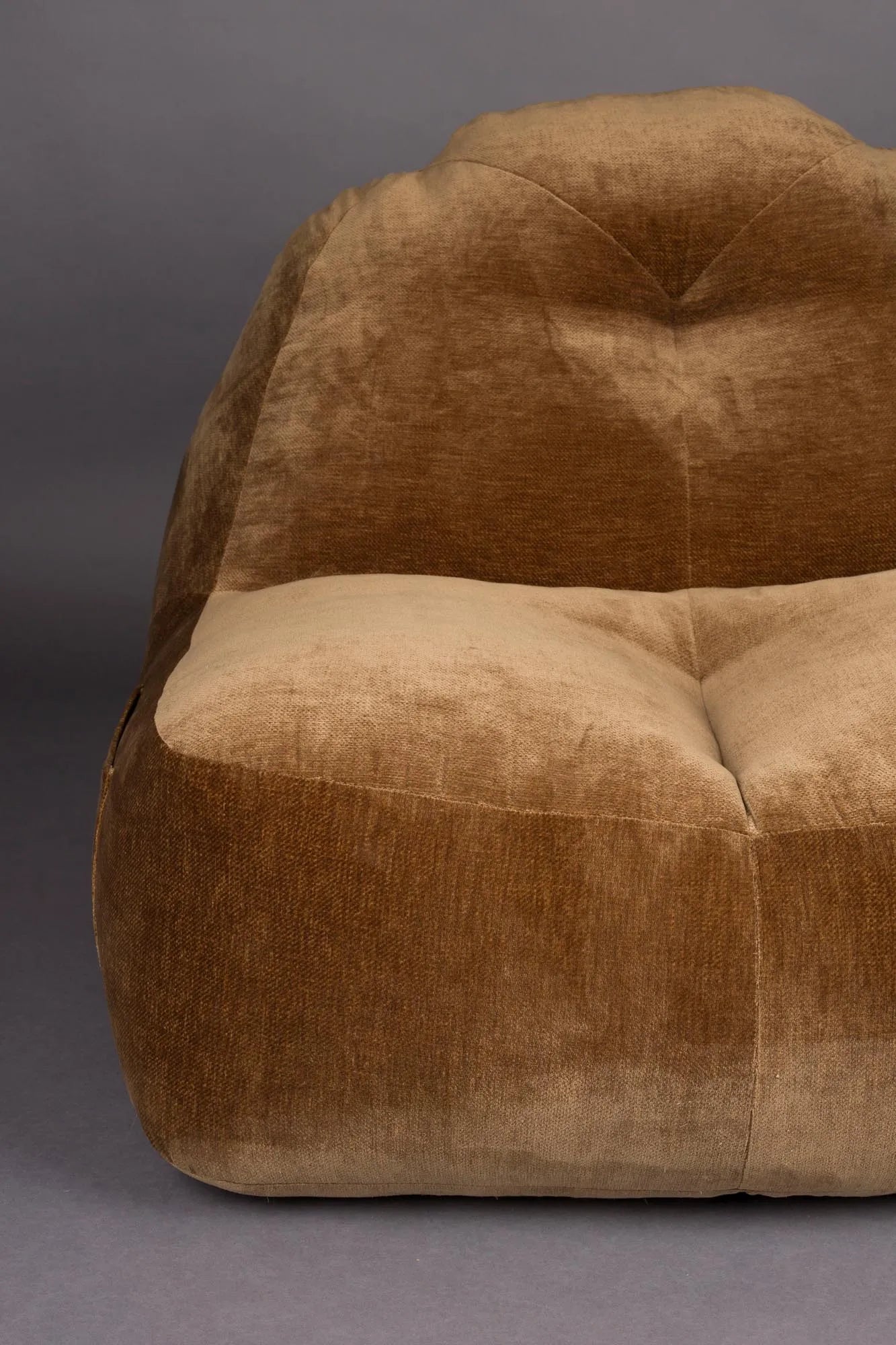 Der Loungesessel Tombag von Dutchbone: Stilvoller Komfort mit samtiger Oberfläche, praktischer Seitentasche und nostalgischem Flair.