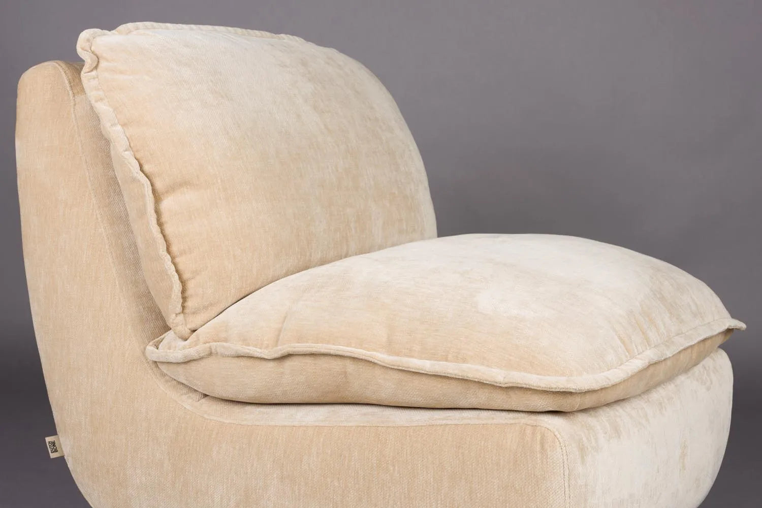 Der Loungesessel Radley von Dutchbone vereint Komfort und Stil mit weichen Kissen und eleganten Holzbeinen für Ihr Zuhause.