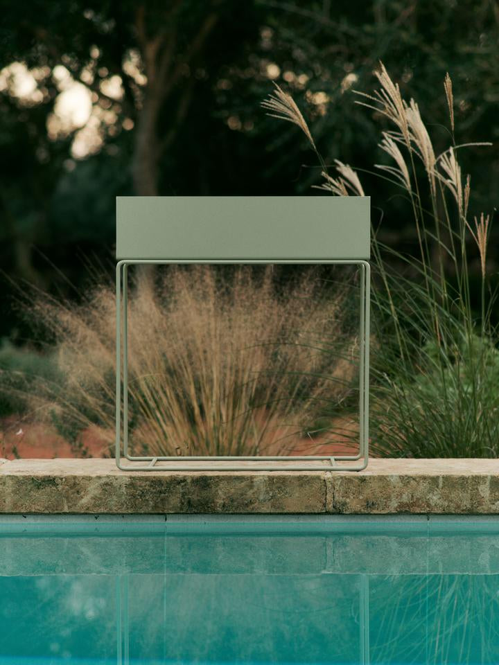Entdecken Sie die stilvolle Plant Box von Ferm Living in Teegrün – ideal für Ihre Pflanzen und ein echter Hingucker für jeden Außenbereich.