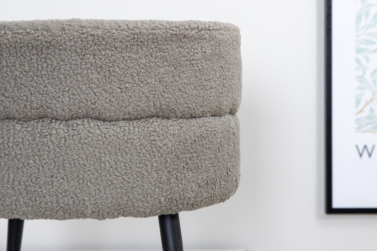 Runder Pouf Pot in Grau mit Teddystoff-Bezug, Durchmesser 40 cm, auf schwarzen, leicht ausgestellten Stahlbeinen stehend.