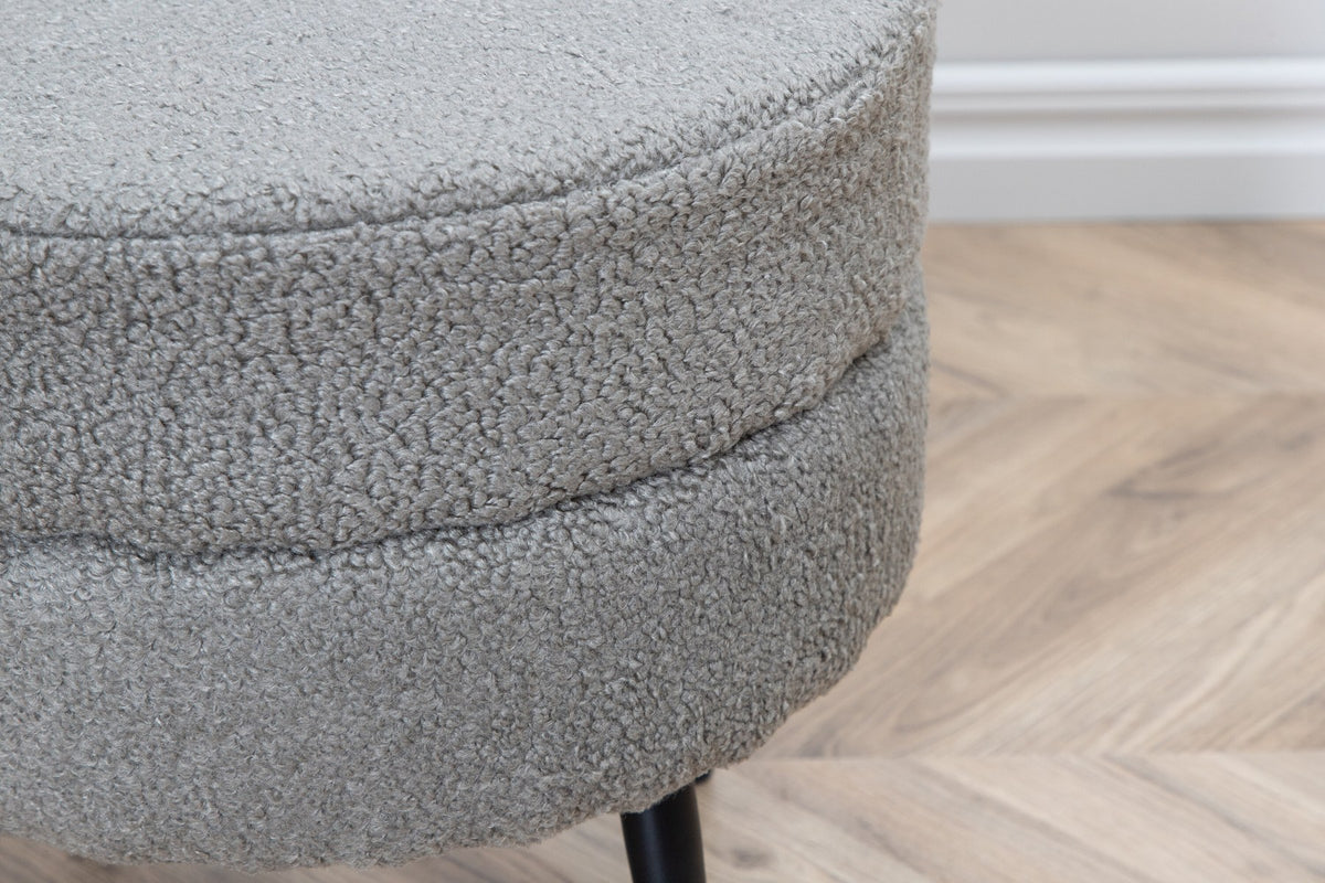 Runder Pouf Pot in Grau mit Teddystoff-Bezug, Durchmesser 40 cm, auf schwarzen, leicht ausgestellten Stahlbeinen stehend.