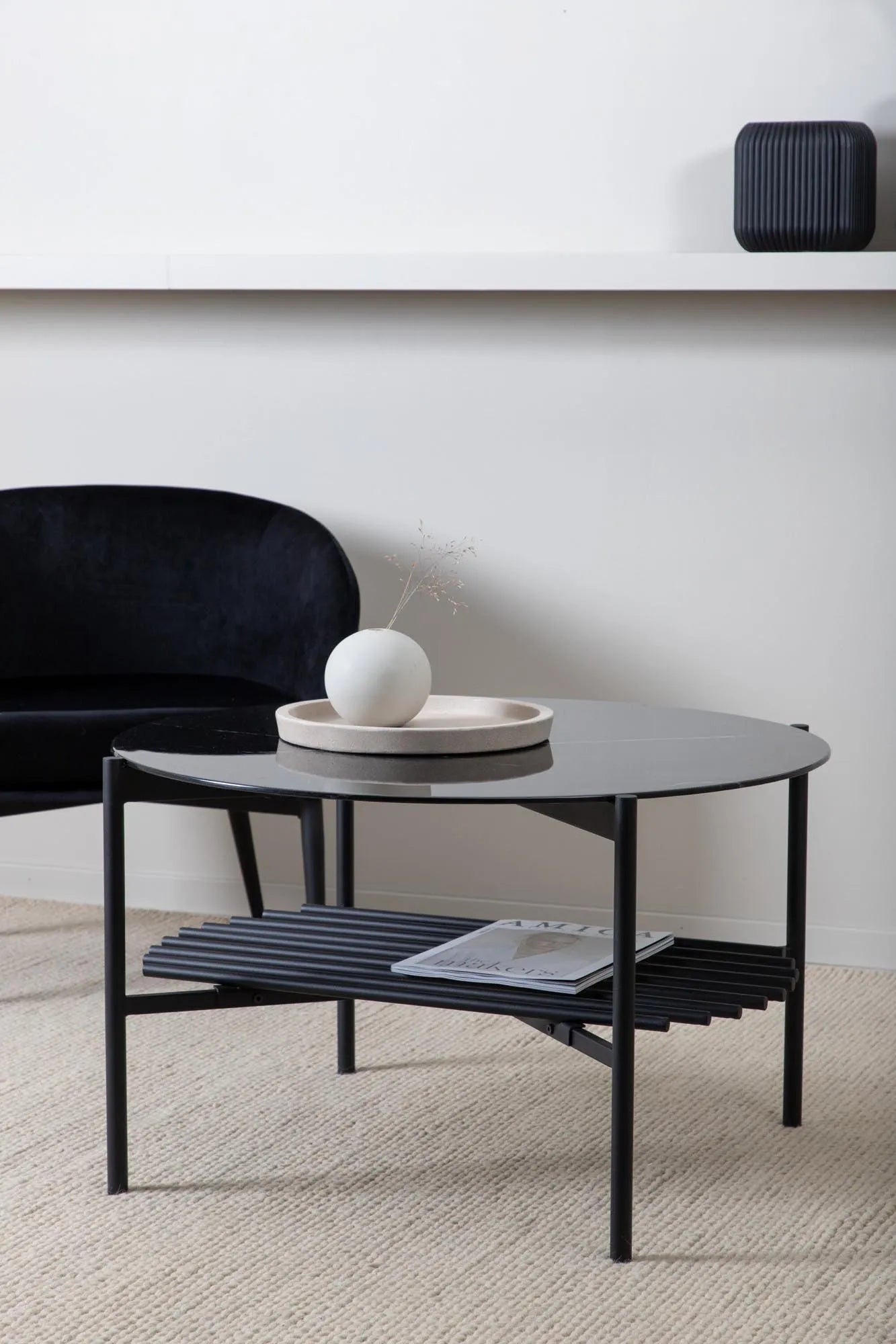 Moderner runder Couchtisch mit Marmorglasplatte und schwarzem Metallrahmen, ideal für stilvolle Wohnräume.