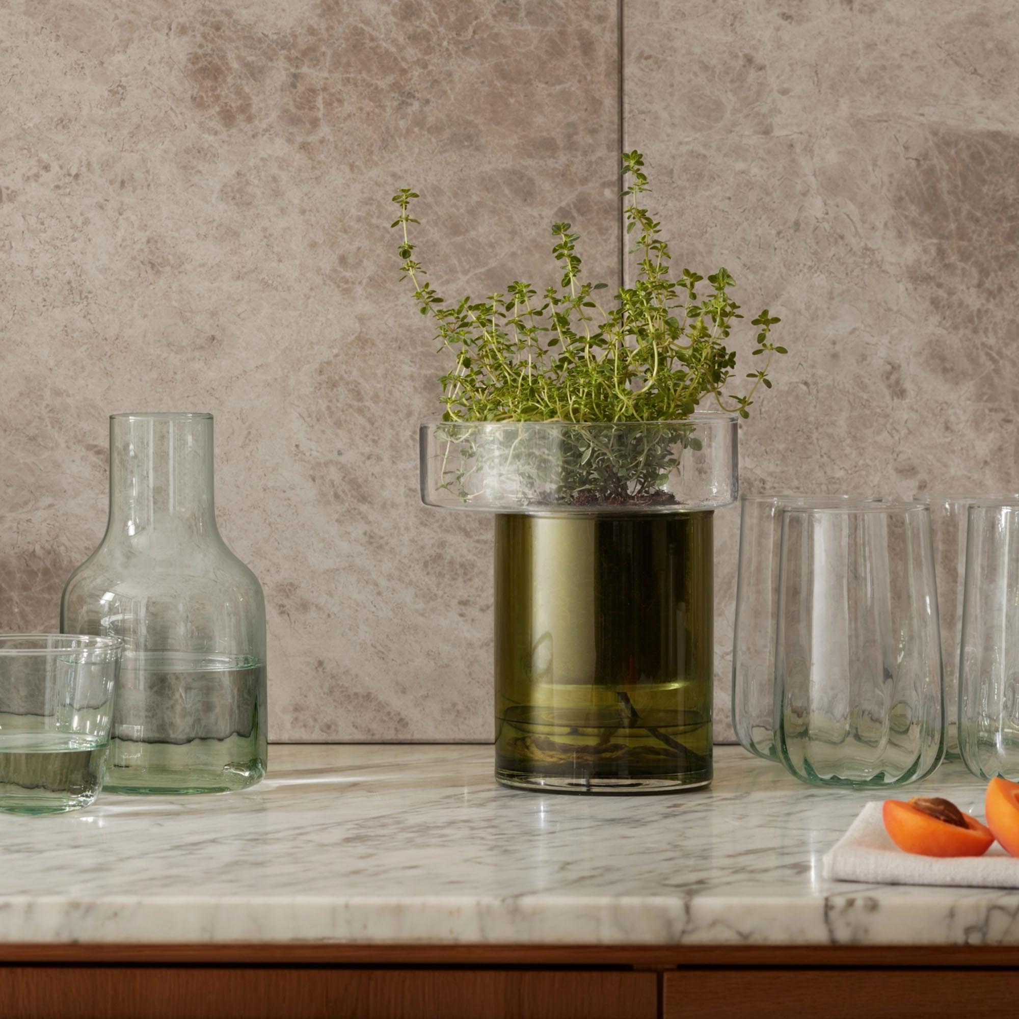 Eleganter selbstwässernder Pflanzentopf von LSA in klarem Glas und olivgrüner Kordel, ideal für Balkon und Terrasse.