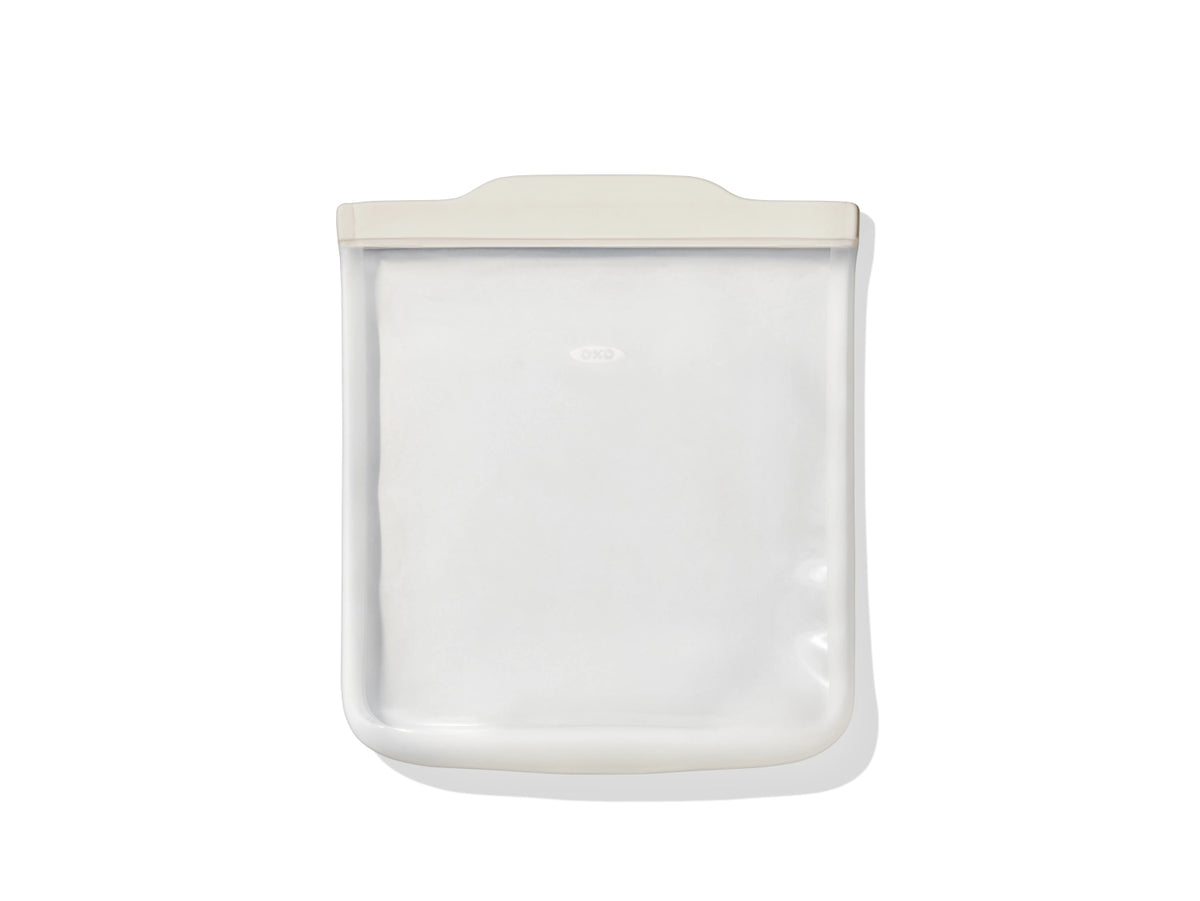 Transparente Silikon-Aufbewahrungstasche von OXO Good Grips mit flacher, rechteckiger Form und Verschlusslasche, leer abgebildet.