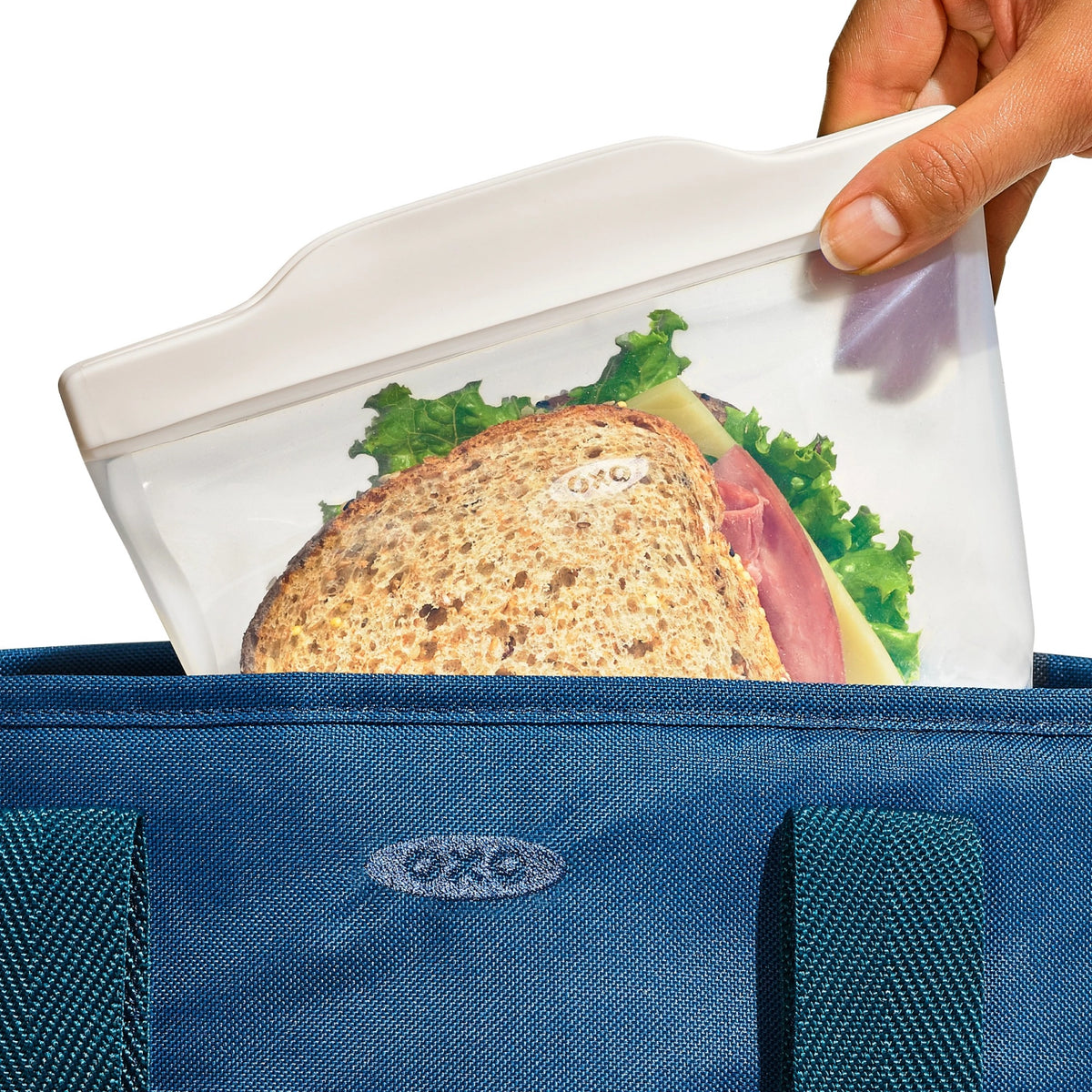 Transparente Silikon-Aufbewahrungstasche von OXO Good Grips mit flacher, rechteckiger Form und Verschlusslasche, leer abgebildet.