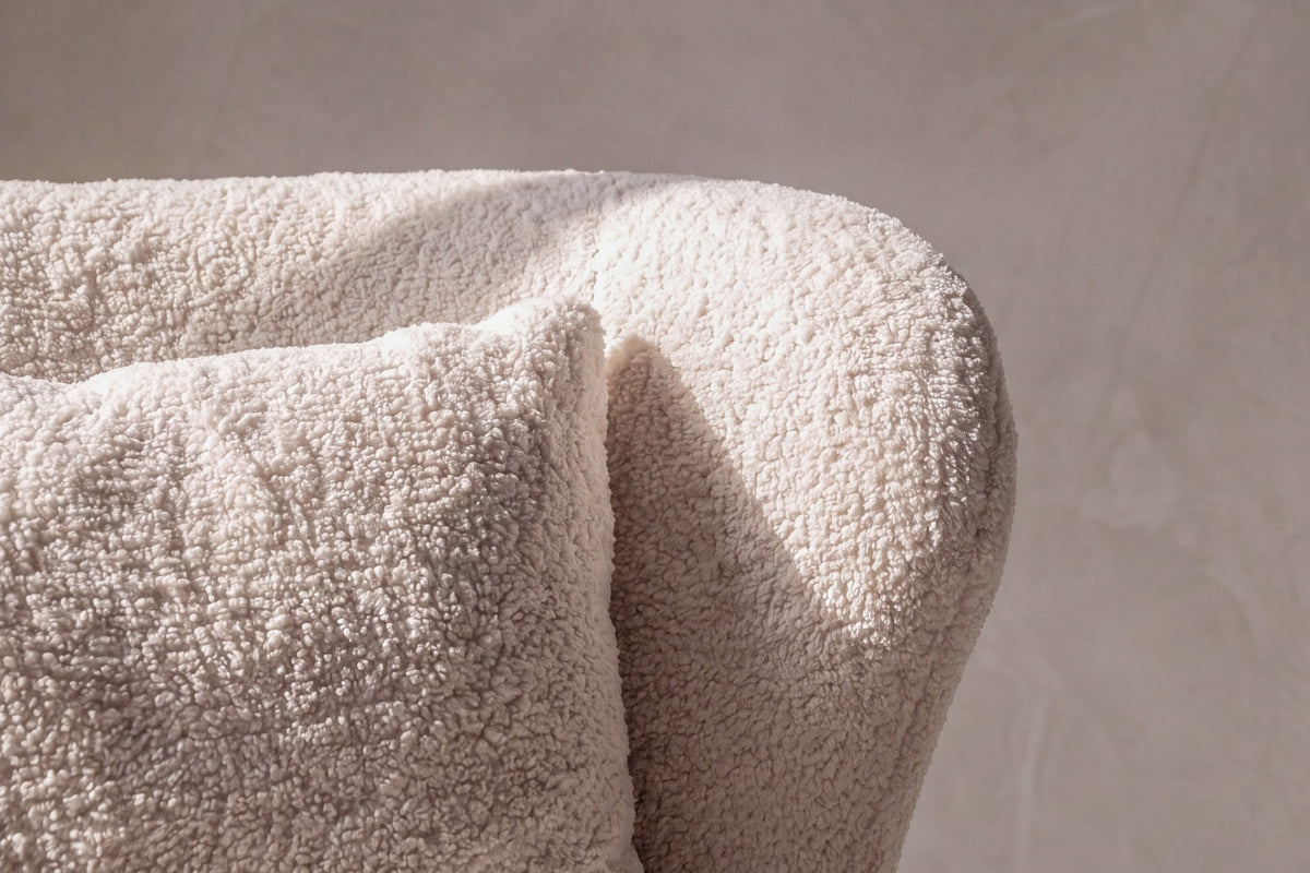 Weisser Loungesessel mit Bouclé-Bezug aus Polyester, Schaumstofffüllung und braunen Stahlbeinen im Holzeffekt-Design, Sitzhöhe 43 cm.