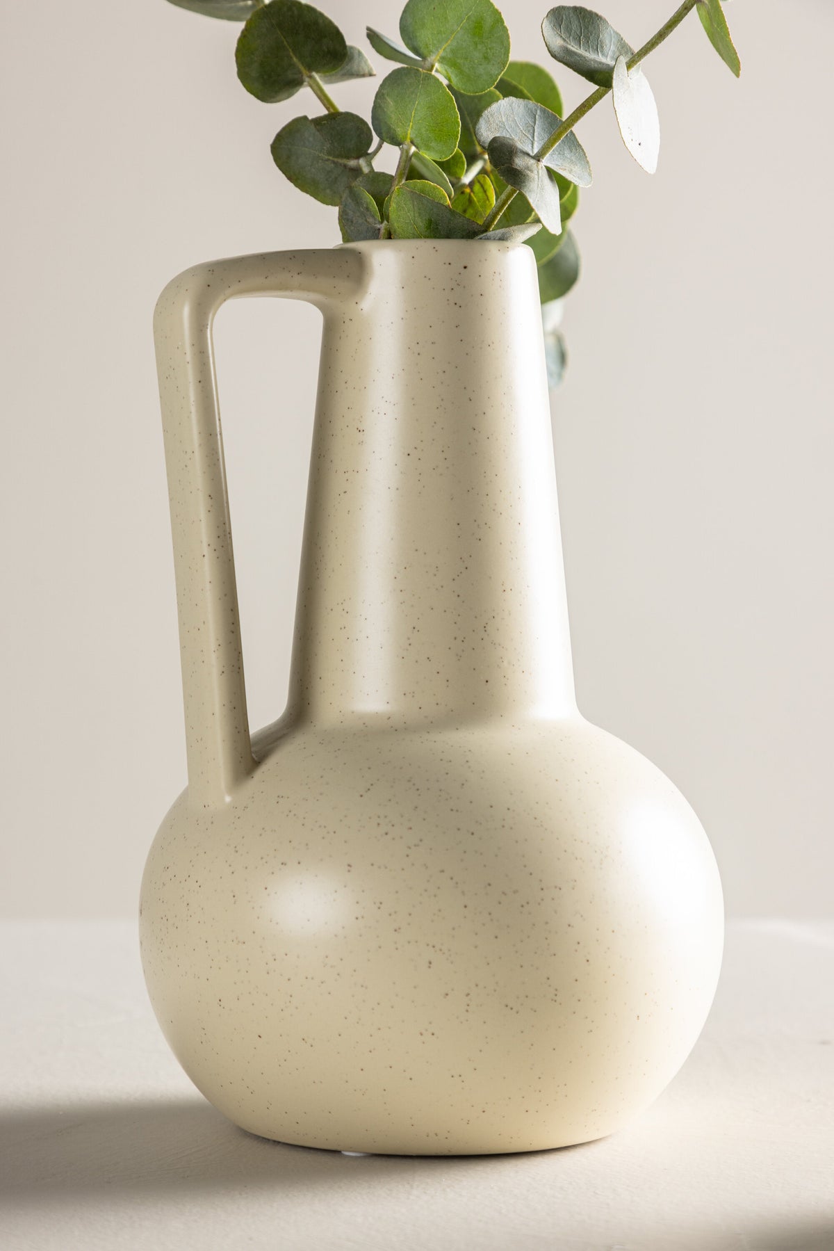 Zylindrische Vase aus Steinzeug in Beige und Schwarz mit seitlichem Griff, matte Oberfläche, Höhe 22 cm, Durchmesser 10 cm.