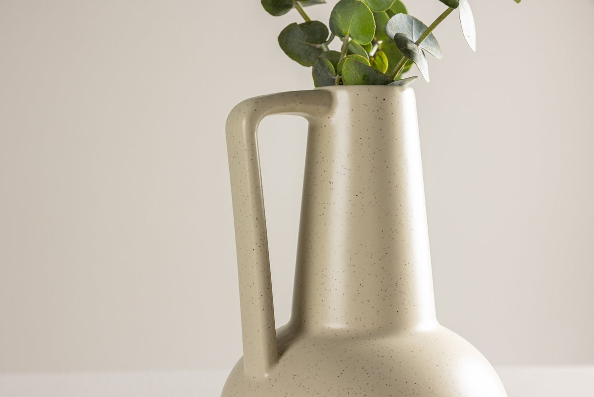 Zylindrische Vase aus Steinzeug in Beige und Schwarz mit seitlichem Griff, matte Oberfläche, Höhe 22 cm, Durchmesser 10 cm.