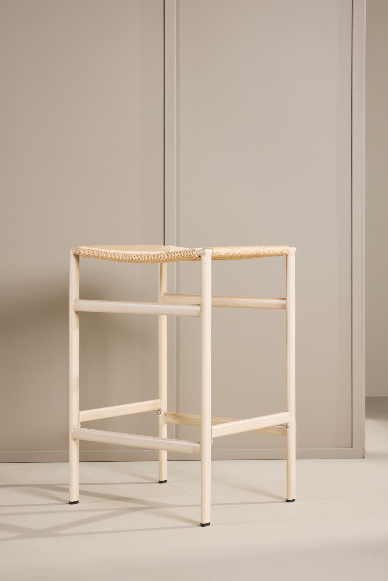 Der Polly Barstuhl vereint Rattan-Sitz und weiße Holzbeine zu einem stilvollen, platzsparenden Design für modernen Boho-Chic.