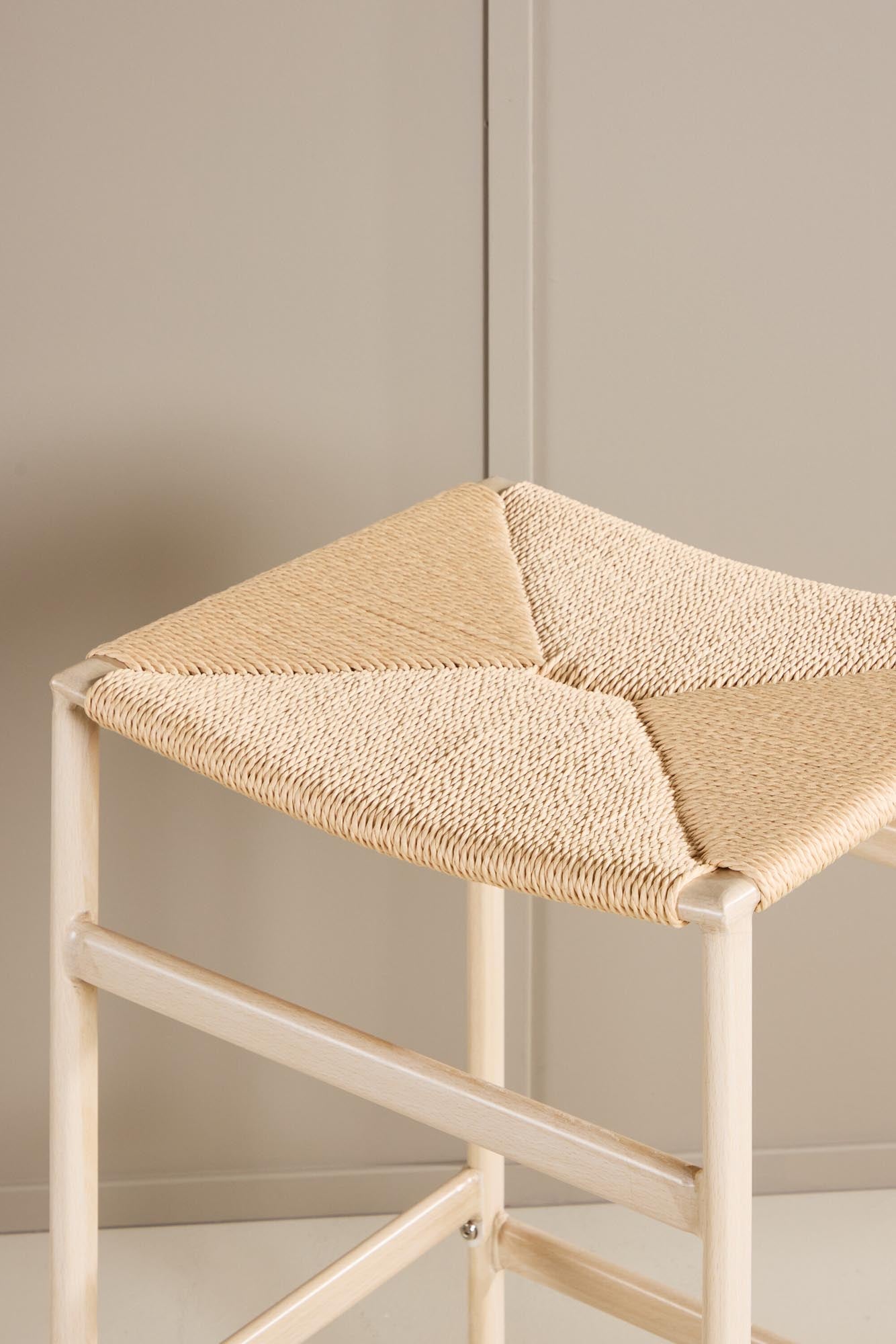 Der Polly Barstuhl vereint Rattan-Sitz und weiße Holzbeine zu einem stilvollen, platzsparenden Design für modernen Boho-Chic.