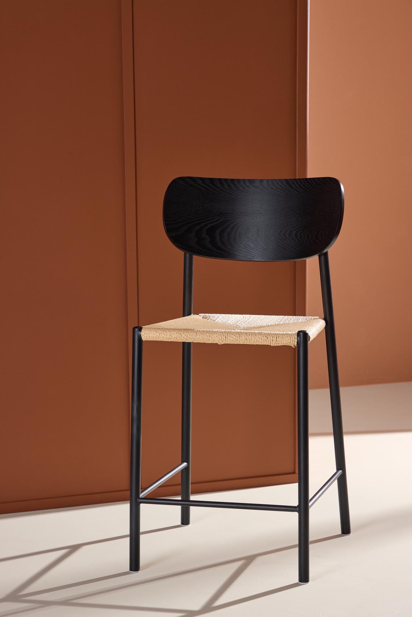 Der Polly Barstuhl vereint Rattan-Sitz und weiße Holzbeine zu einem stilvollen, platzsparenden Design für modernen Boho-Chic.