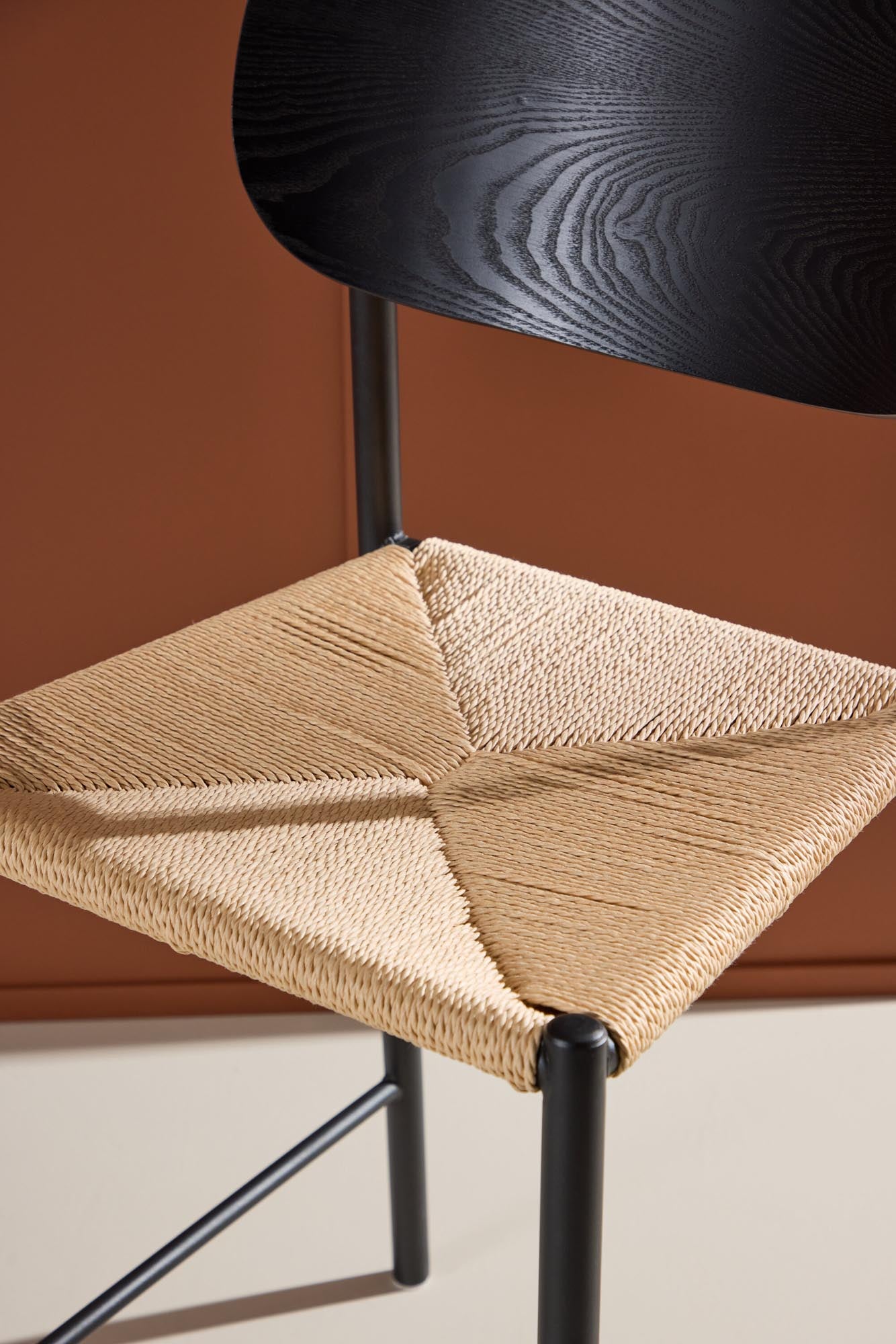 Der Polly Barstuhl vereint Rattan-Sitz und weiße Holzbeine zu einem stilvollen, platzsparenden Design für modernen Boho-Chic.