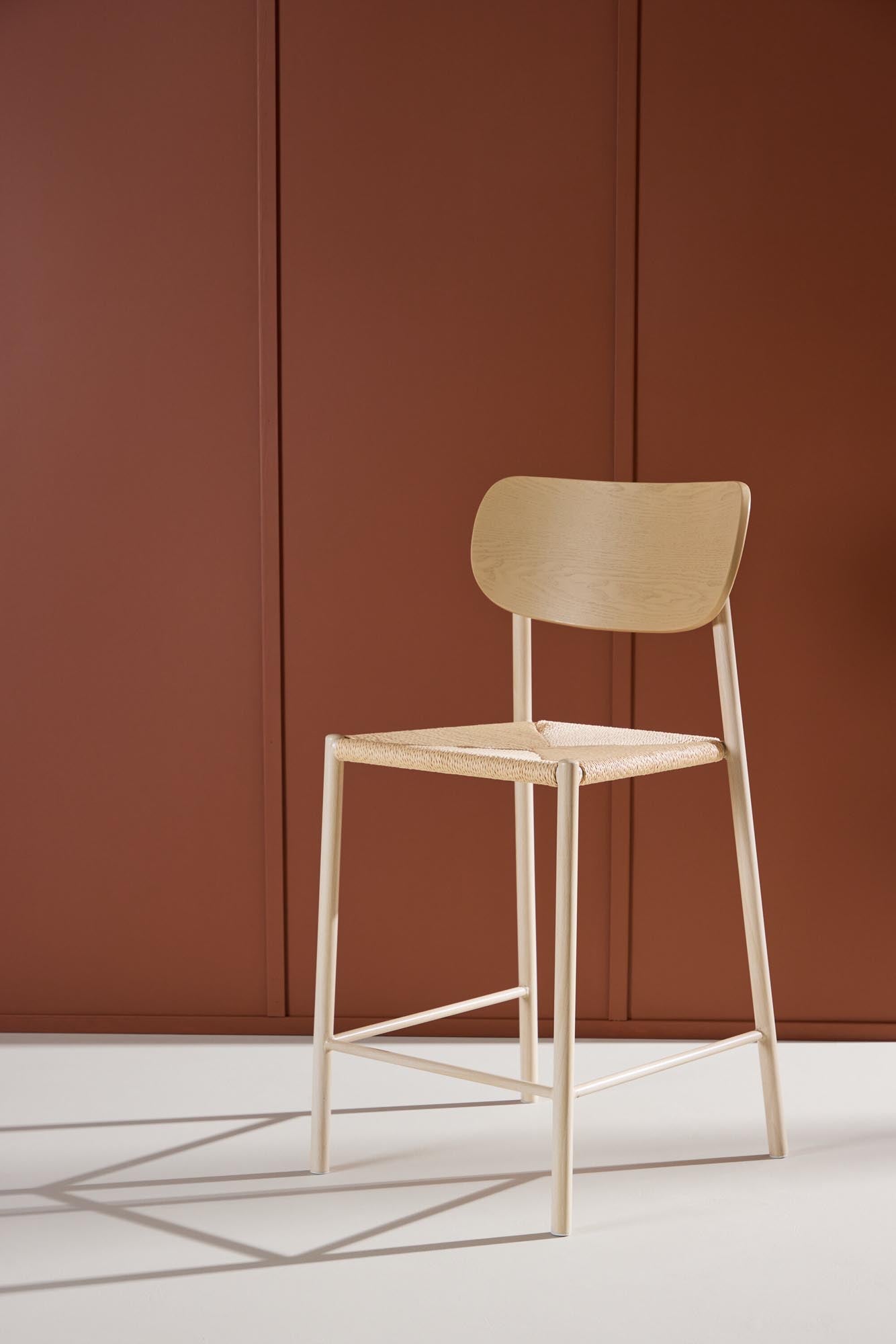 Der Polly Barstuhl vereint Rattan-Sitz und weiße Holzbeine zu einem stilvollen, platzsparenden Design für modernen Boho-Chic.