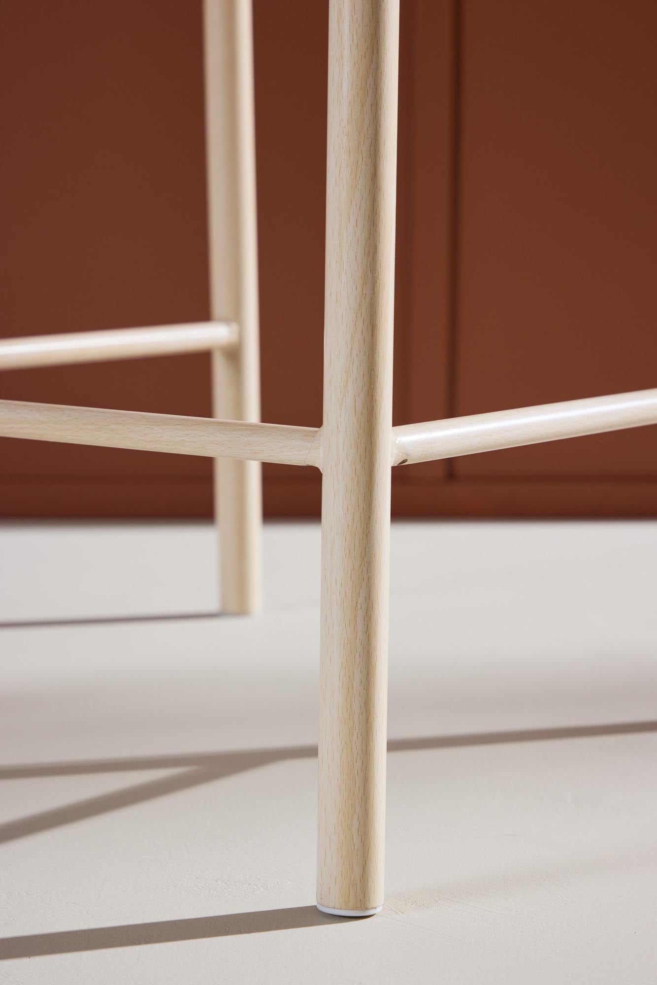 Der Polly Barstuhl vereint Rattan-Sitz und weiße Holzbeine zu einem stilvollen, platzsparenden Design für modernen Boho-Chic.