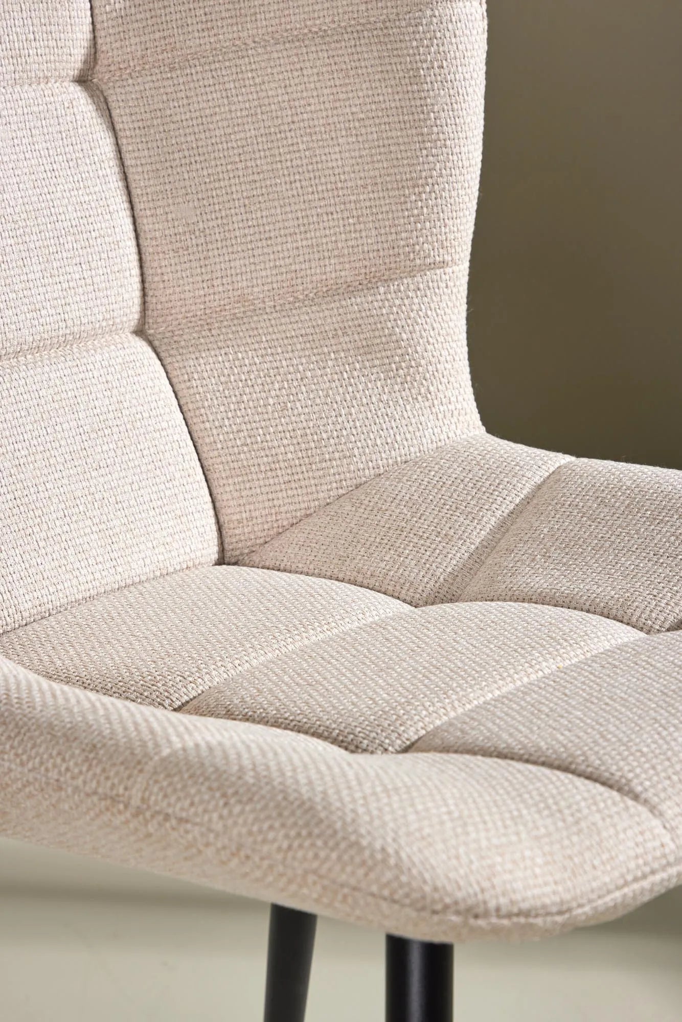 Der Lily Esszimmerstuhl vereint elegantes Design mit Komfort: Beige Polsterung, schwarze Beine, ideal für stilvolle Esszimmer.