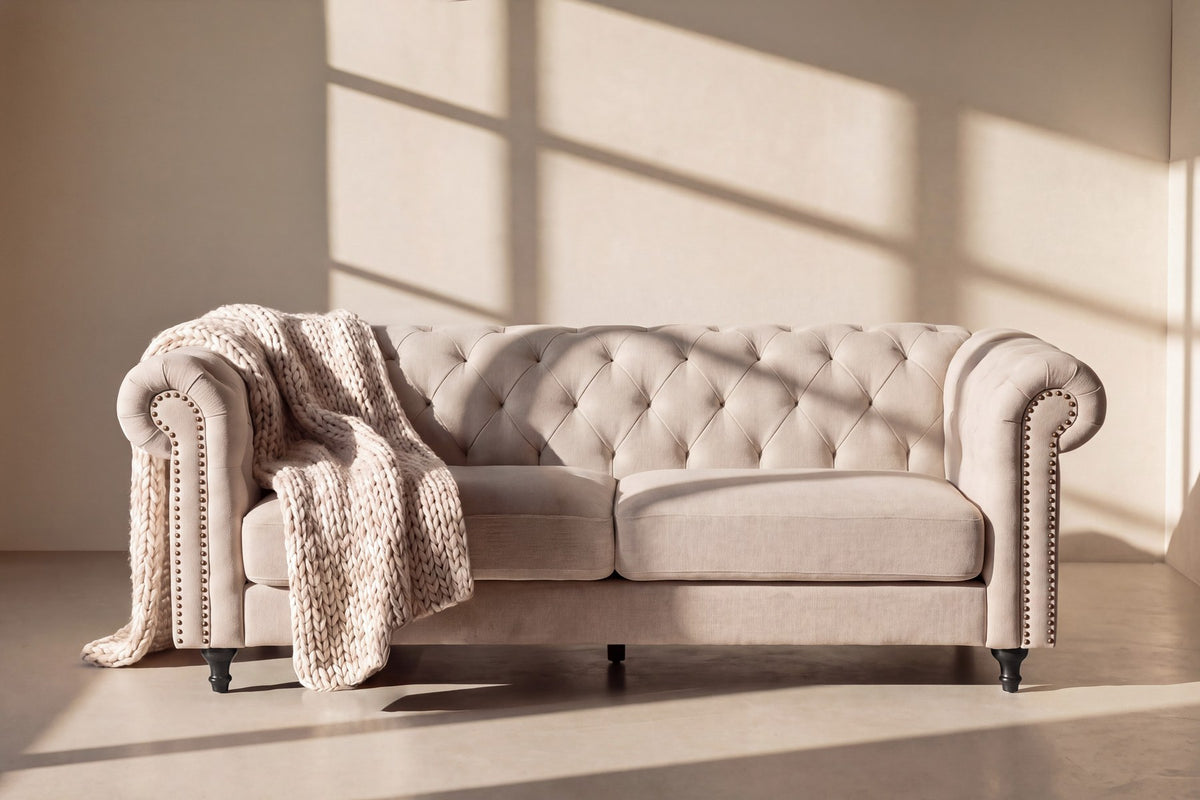Beiges 3-Sitzer-Sofa Velvet von Venture Home mit Polyester-Samt-Bezug, tiefer Knopfheftung und schwarzen Gummibaumholz-Beinen im Chesterfield-Design.