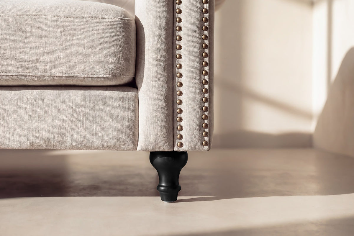 Beiges 3-Sitzer-Sofa Velvet von Venture Home mit Polyester-Samt-Bezug, tiefer Knopfheftung und schwarzen Gummibaumholz-Beinen im Chesterfield-Design.