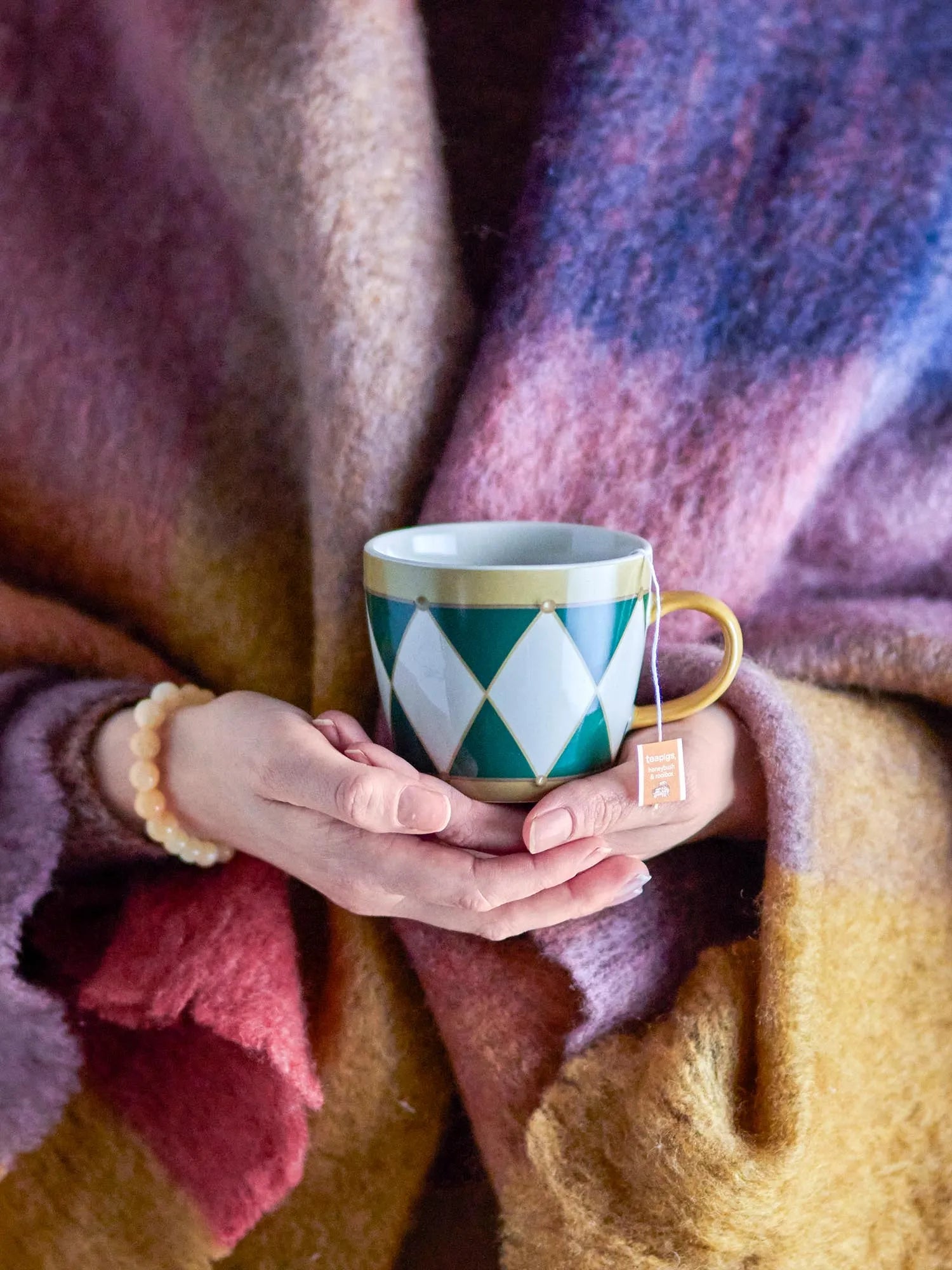 Der Jolly Becher von Bloomingville vereint robustes Steingut mit stilvollem Design: grüne Töne, goldener Griff, geometrische Muster.