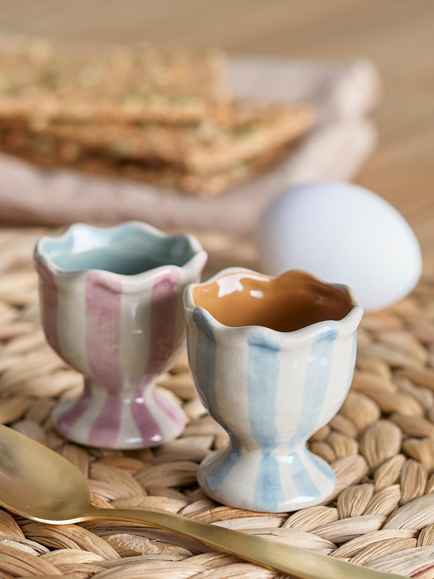 Elegante Eierbecher aus Steingut in Rosé mit handbemalten Streifen, robust und spülmaschinenfest, ideal für stilvolle Frühstücke.
