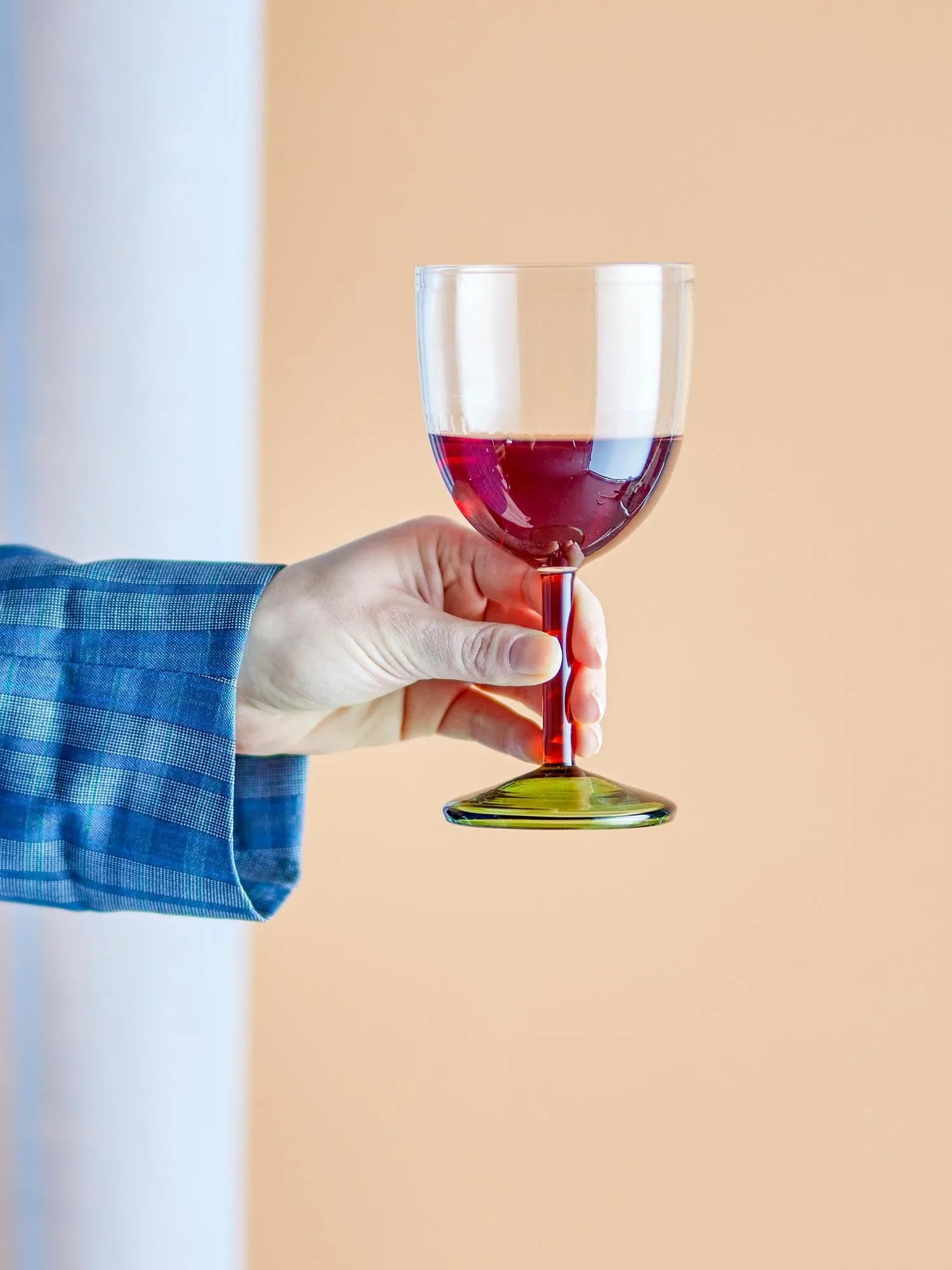 Elegantes Weinglas mit rotem Stiel und grünem Fuß, ideal für stilvolle Tischdekorationen.
