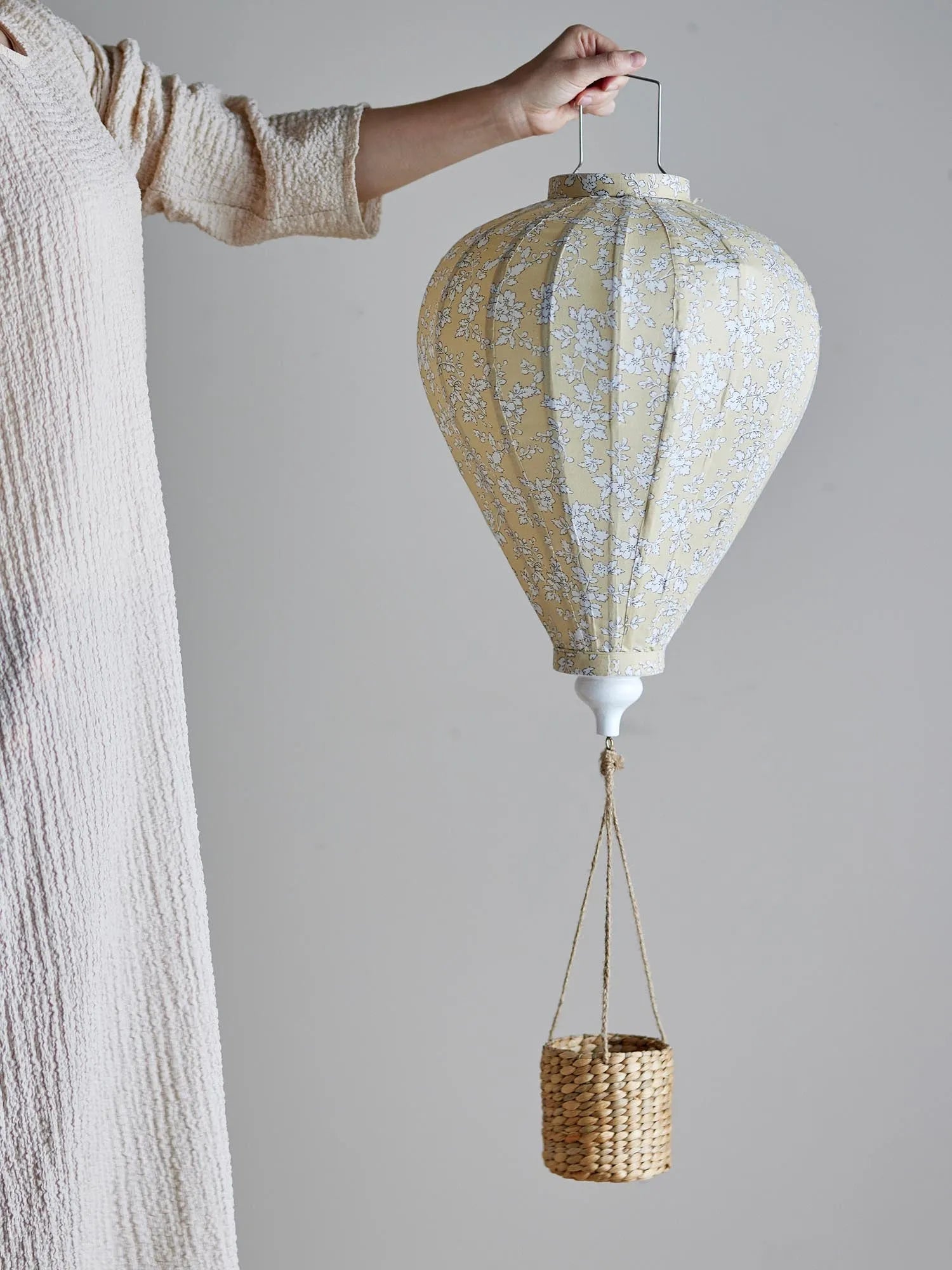 Ein zauberhaftes, gelbes Heißluftballon-Mobile mit Blumenmuster und Lichterkette, ideal für das Kinderzimmer.