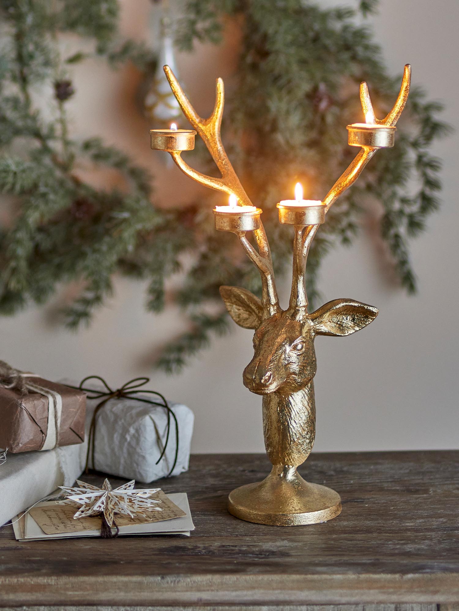 Eleganter Teelichthalter aus Metall in Gold, Hirschkopf-Design, reflektiert Licht für stimmungsvolle Atmosphäre.